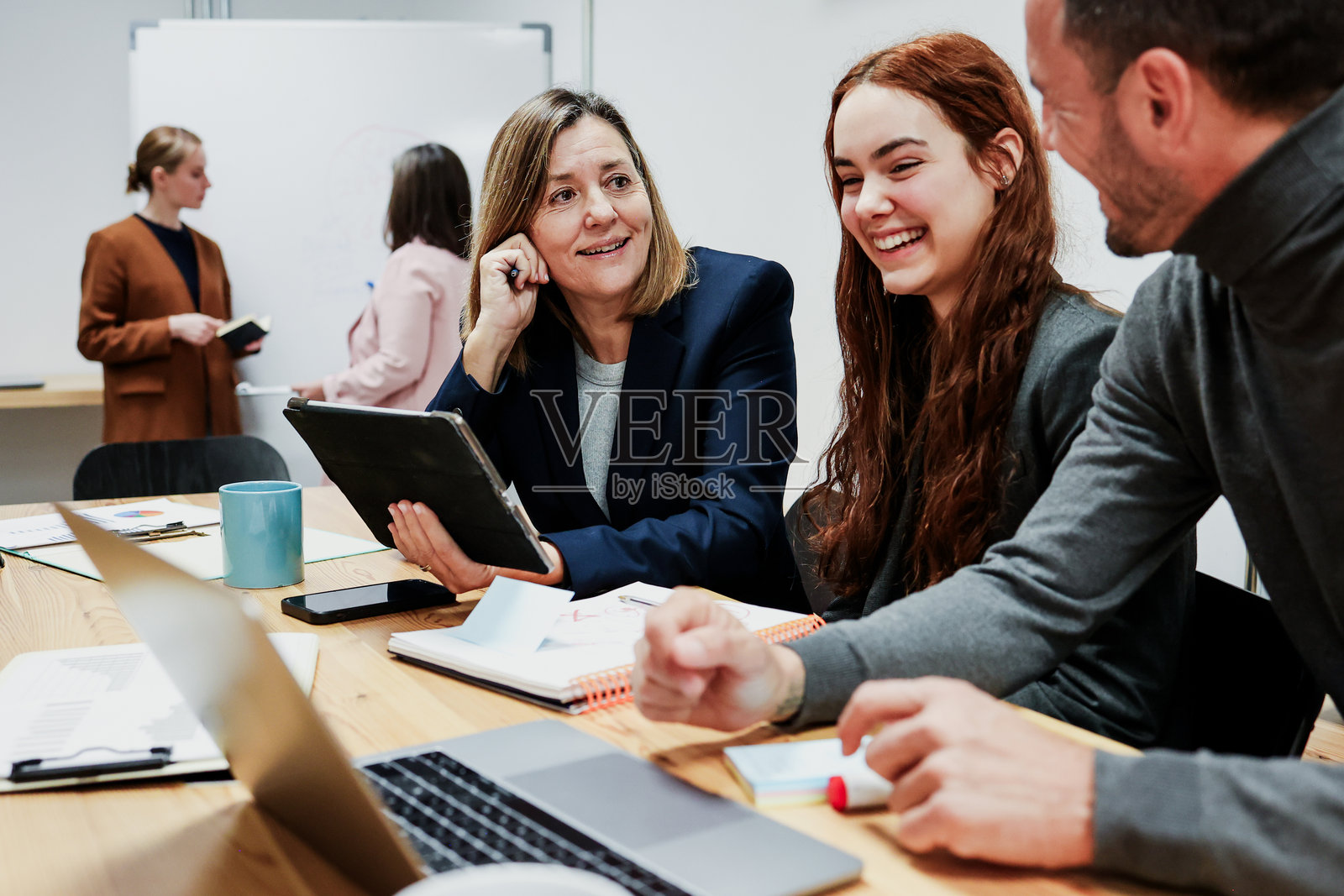 一群不同年龄的西班牙裔商务团队在办公室一起工作并使用笔记本电脑。多元化的创业者和跨代团队分享想法。照片摄影图片