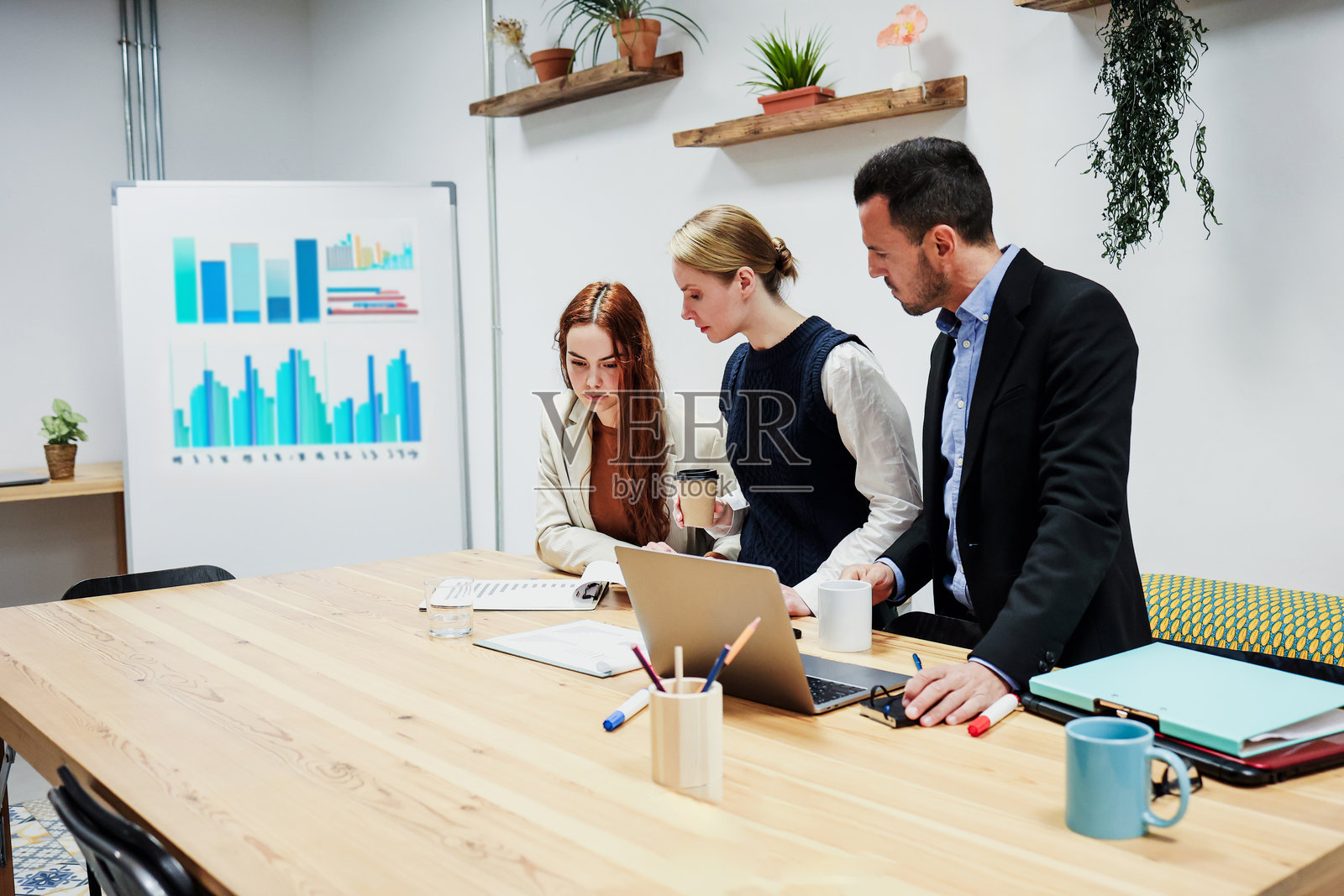 一群不同年龄的西班牙裔商务团队在办公室一起工作并使用笔记本电脑。多元化的创业者和跨代团队分享想法。照片摄影图片