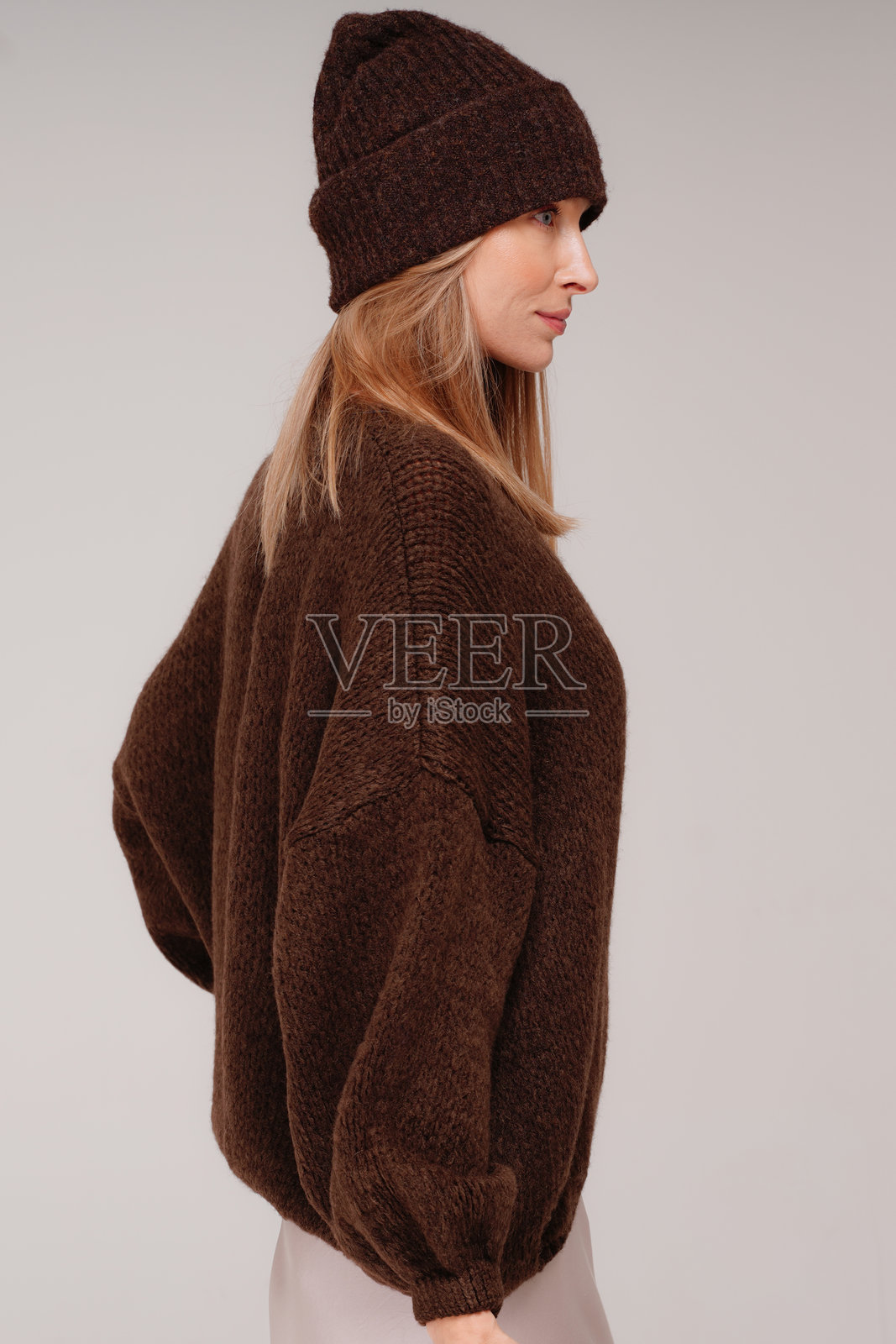 一位美丽、时尚的金发成年女性，身穿时髦的棕色毛衣和冬季帽子照片摄影图片