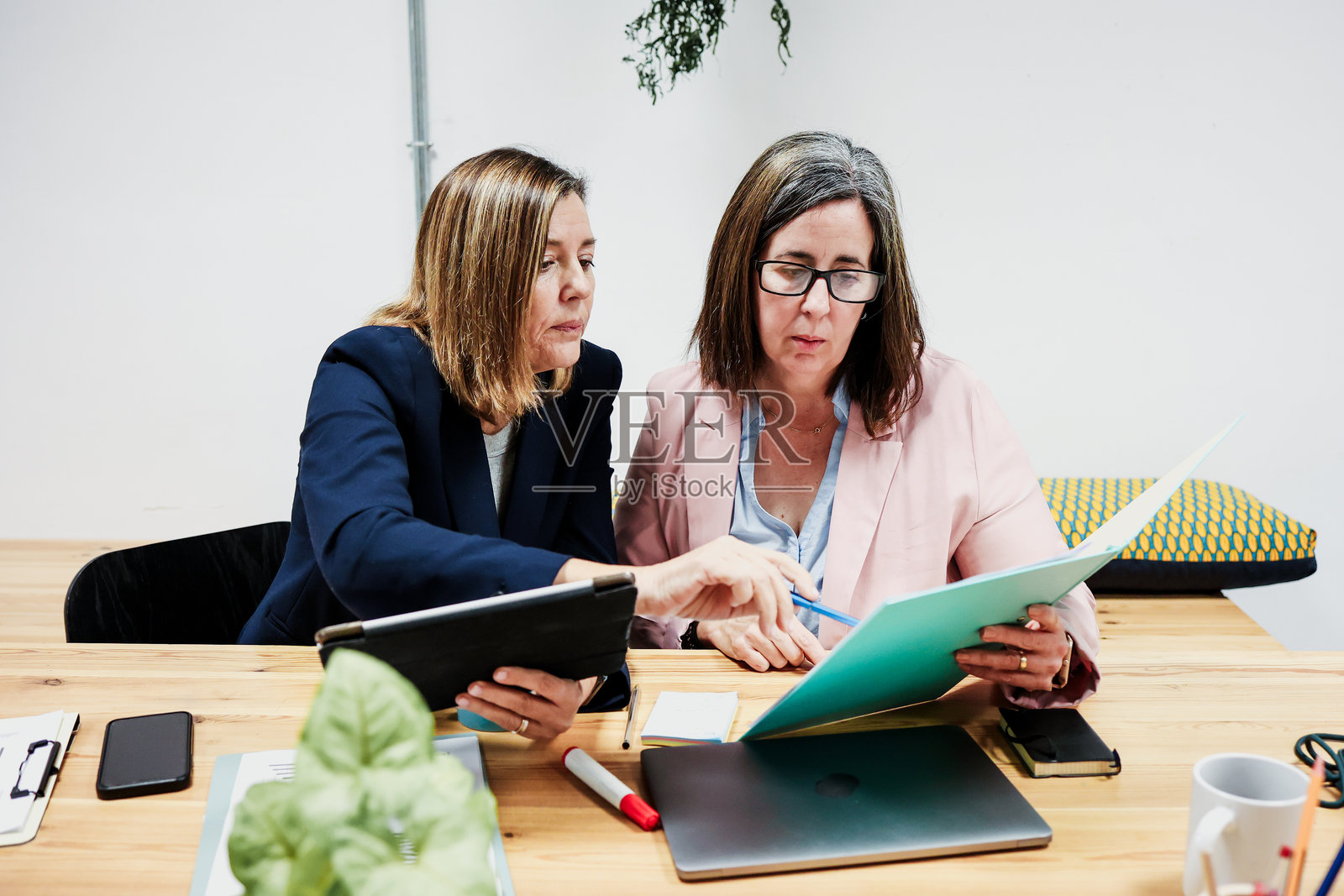 在办公室工作的西班牙裔年长女性，一起使用笔记本电脑。几位成熟的女企业家正在开会并分享想法。照片摄影图片