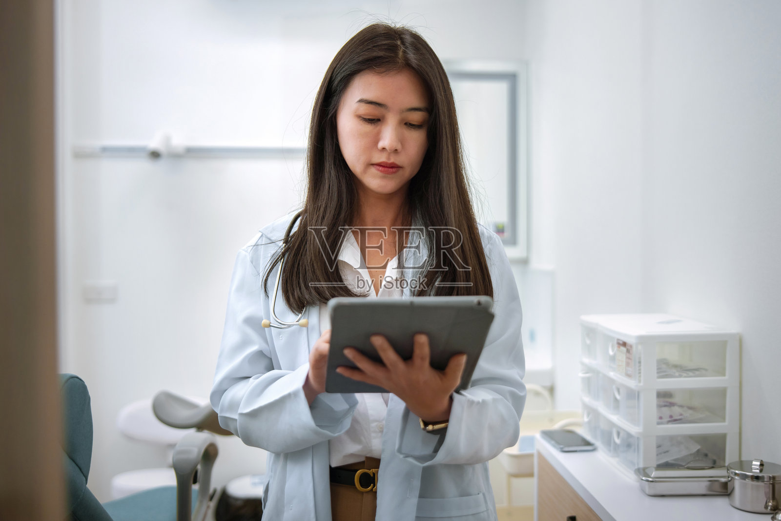 身穿白色实验服的女性正在看平板电脑照片摄影图片