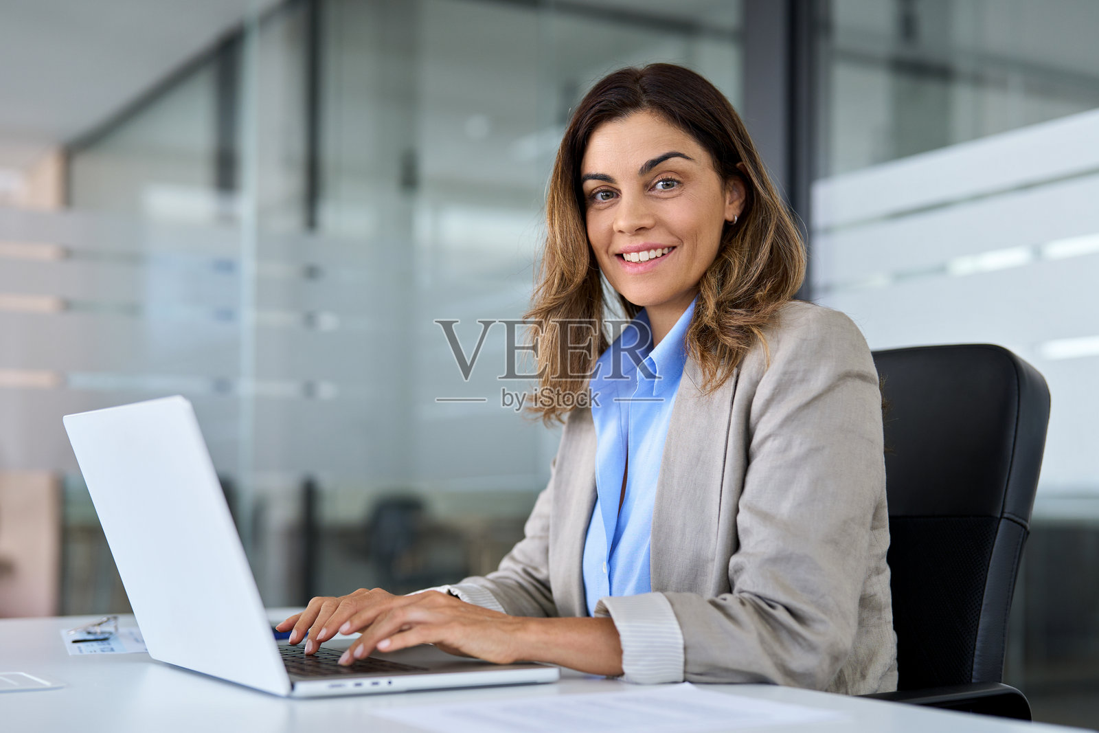 快乐的成熟职业女性，在办公室使用笔记本电脑，肖像照。照片摄影图片