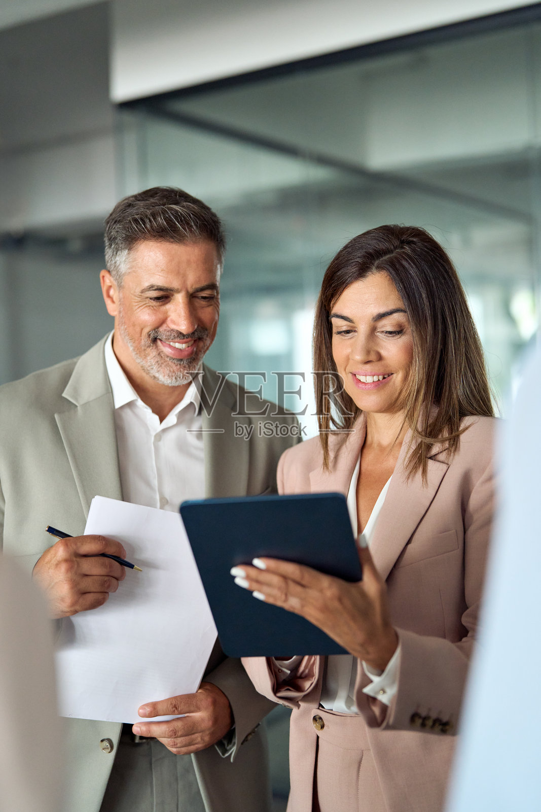 忙碌的商务高管在办公室站着使用平板电脑进行讨论。照片摄影图片