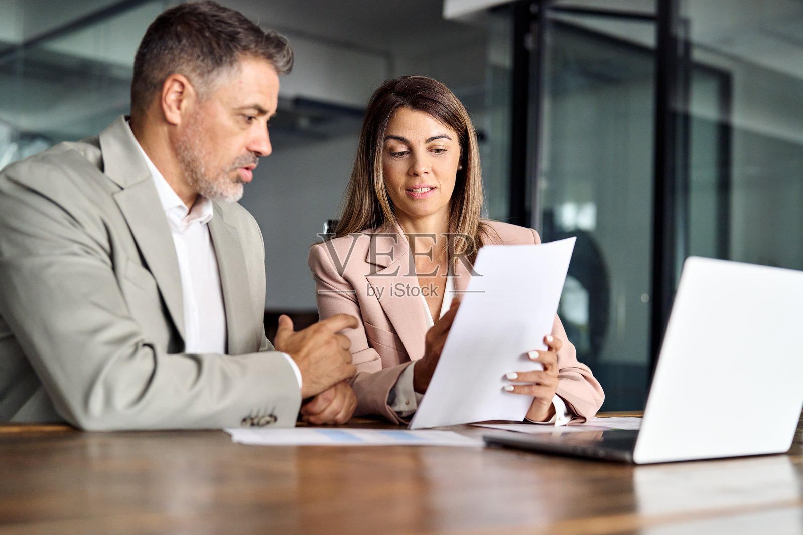 女经理与男客户在会议中协商，展示文件。照片摄影图片