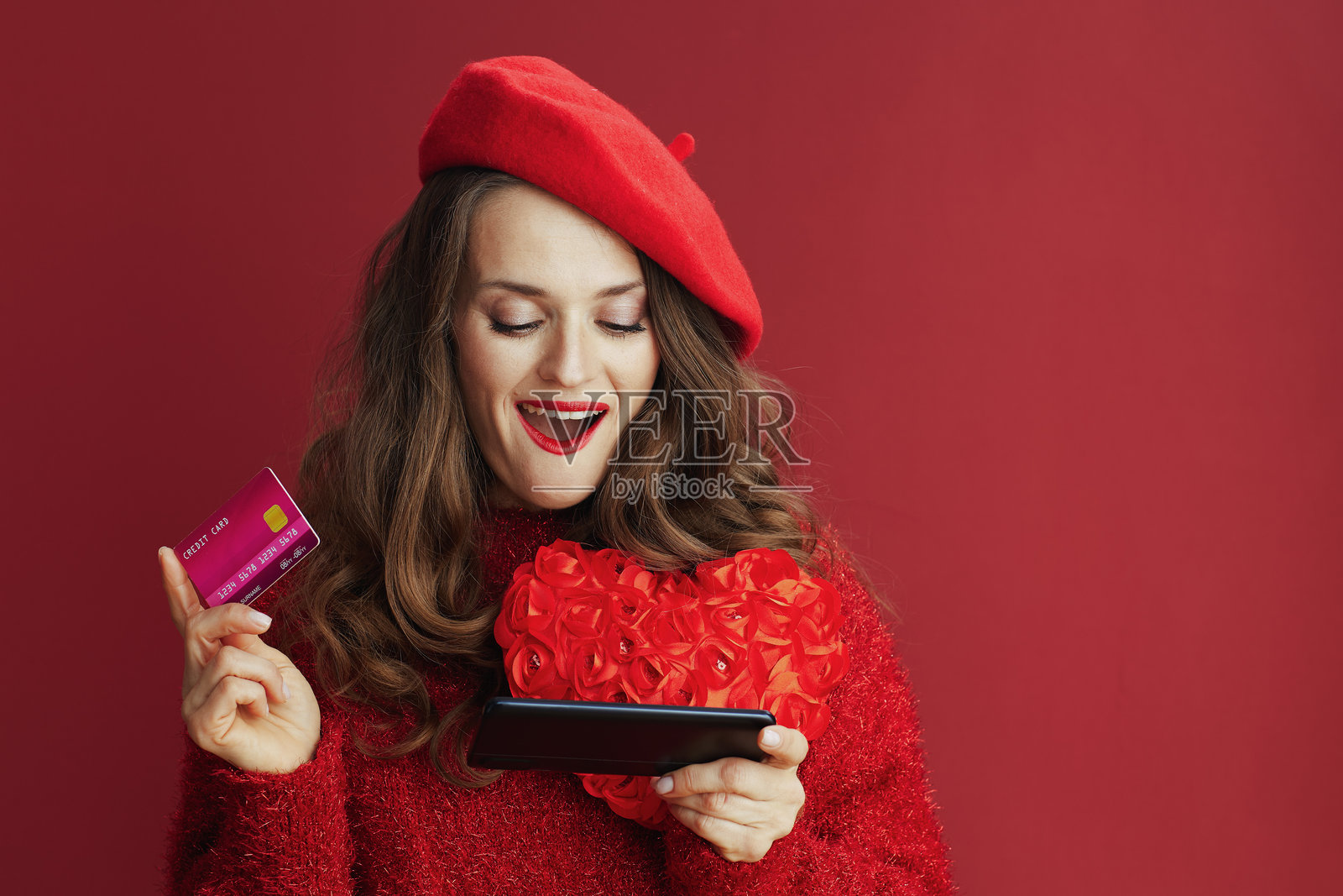 一位衣着时尚的女子，手持红色爱心，惊讶地浏览在线商店照片摄影图片