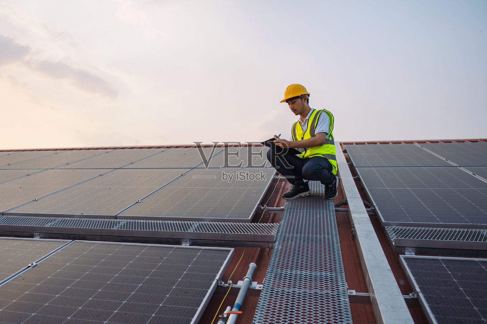 穿着黄色背心的男子正在检查太阳能电池板照片摄影图片