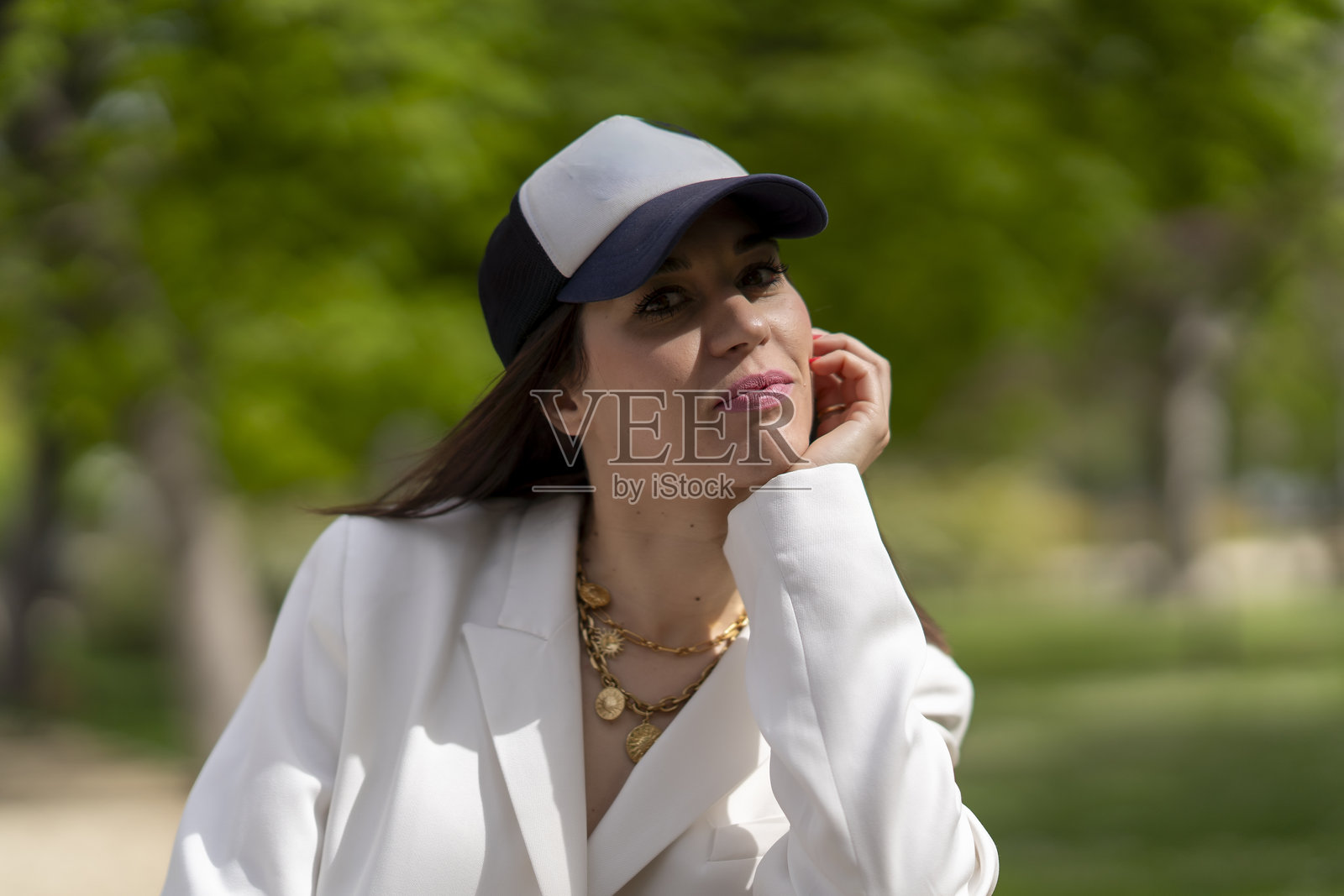 身穿西装外套和棒球帽的女性在户外摆姿势照片摄影图片