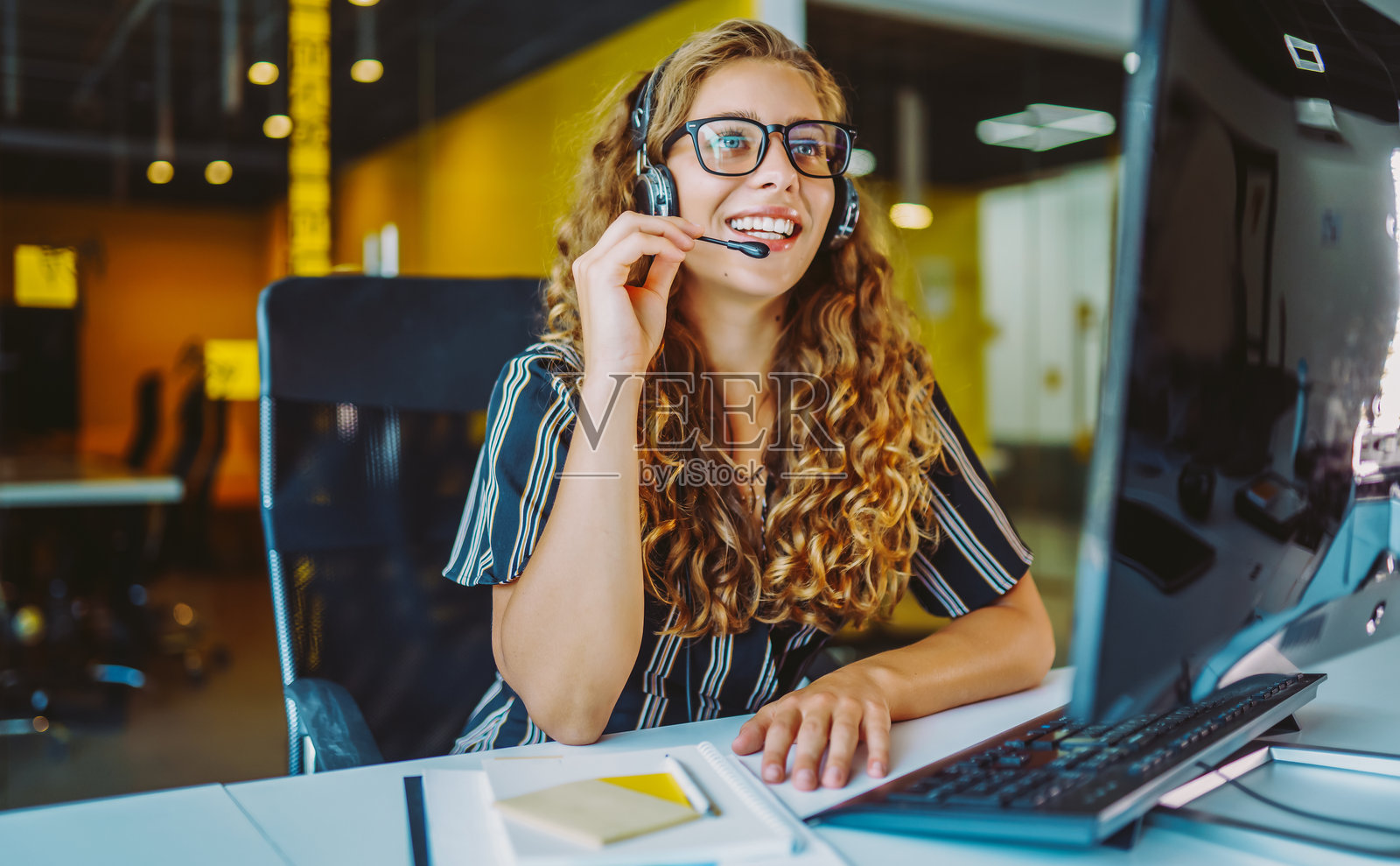 在线会议。一位戴着耳机的年轻女子正在使用笔记本电脑观看网络研讨会或进行视频聊天。照片摄影图片