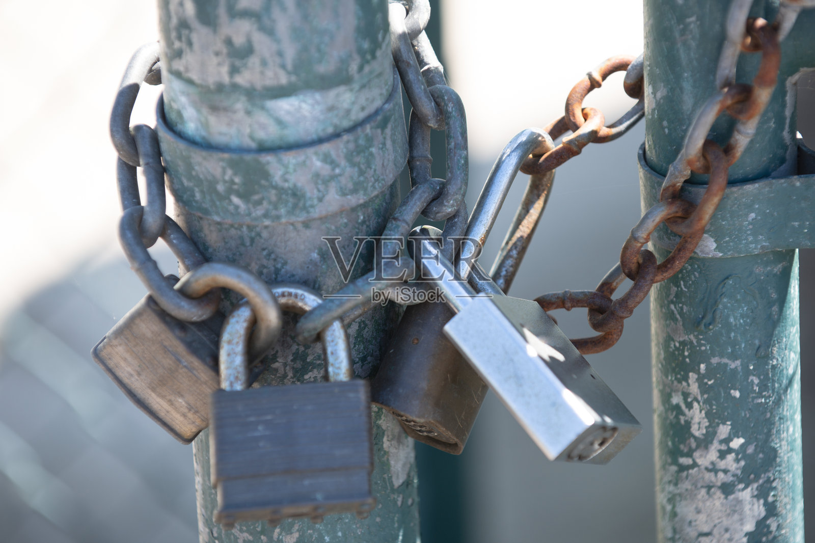 坚固的锁锁住户外的金属门。带有链条的重型锁，展示安全防护。饱经风霜的锁象征着限制通行和安全。锁的特写细节，体现保护与控制。照片摄影图片