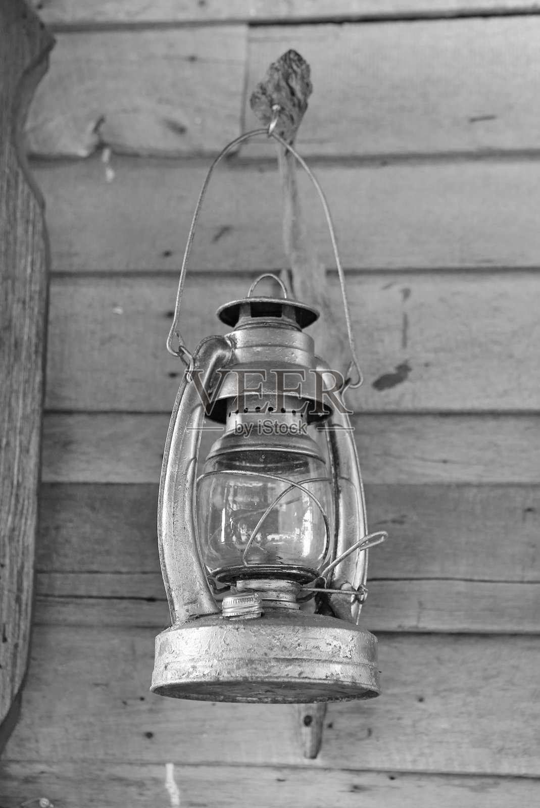 复古煤油灯悬挂在饱经风霜的木墙上，采用经典的黑白风格拍摄。照片摄影图片