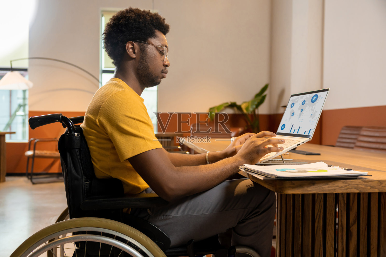 坐轮椅的专注男士正在使用笔记本电脑处理业务数据照片摄影图片