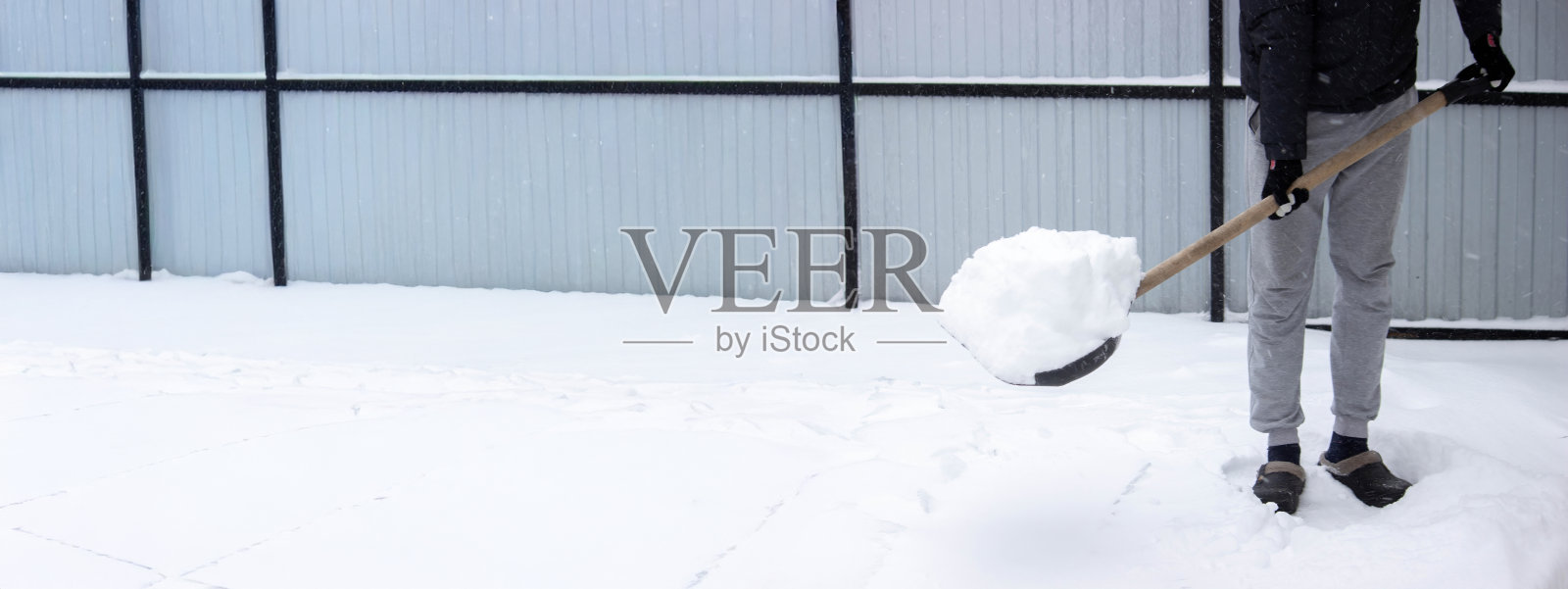 用黑色雪铲铲除新雪，冬季物业维护。照片摄影图片