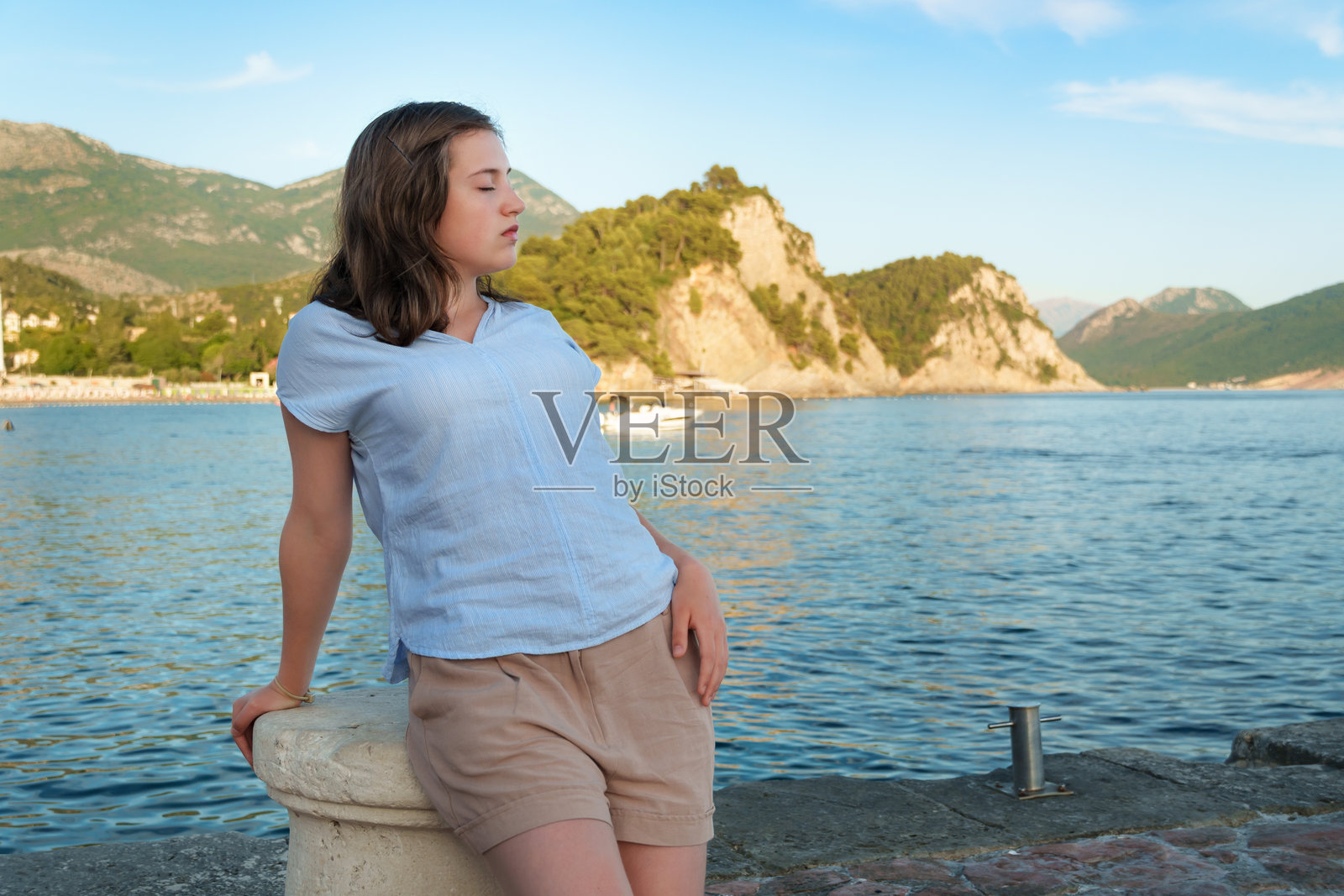 黑山佩特罗瓦茨湾，一位宁静的女孩闭着眼睛享受阳光，夏日悠闲放松的瞬间，中景肖像照片摄影图片