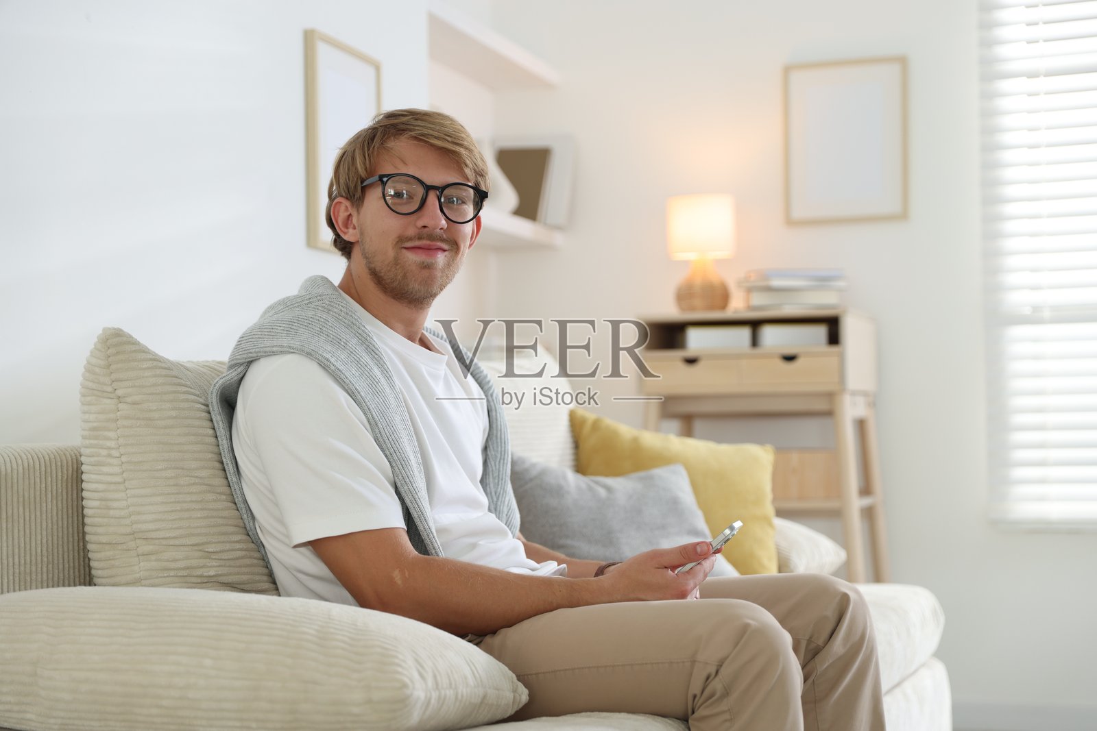 戴眼镜的男人在沙发上用手机照片摄影图片