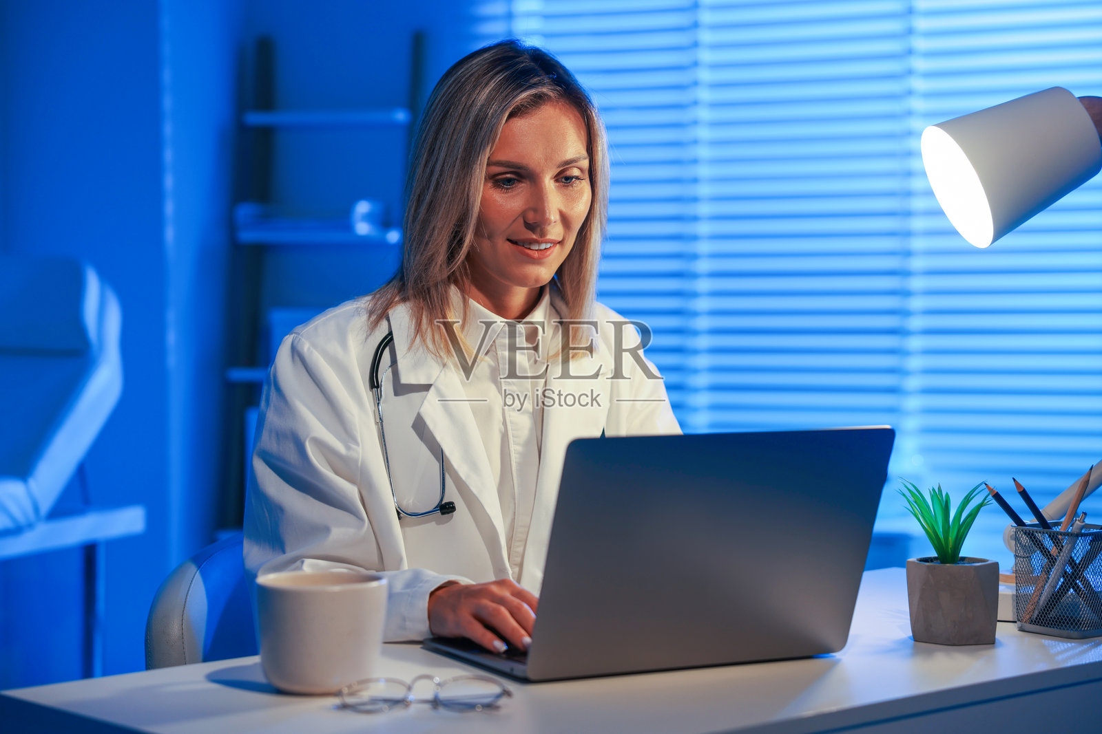 医生在诊所值夜班时在桌边用笔记本电脑工作照片摄影图片