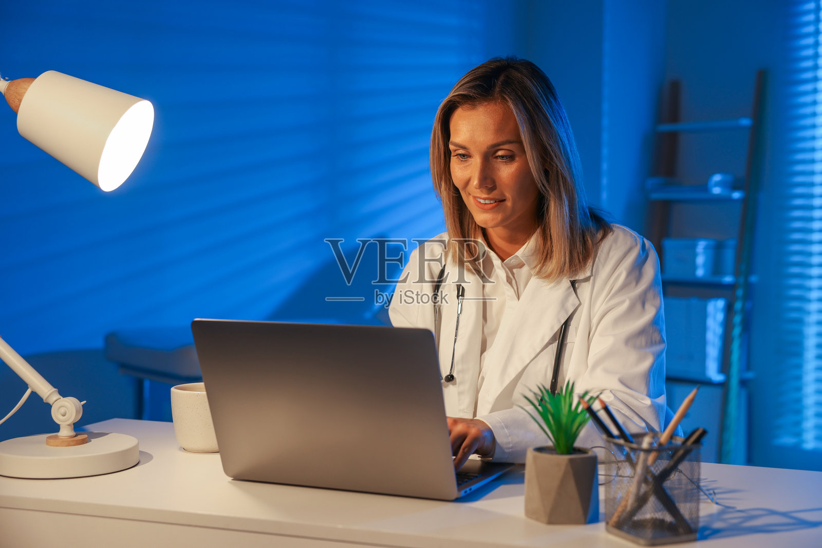 医生在诊所夜班时在桌边使用笔记本电脑工作照片摄影图片