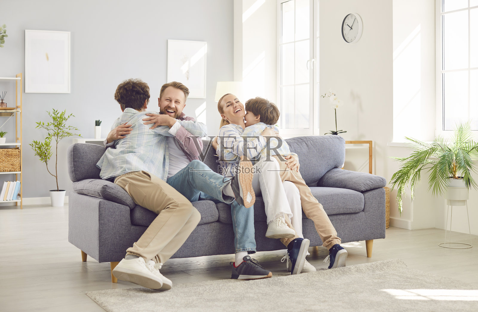 快乐的父母和孩子们正享受着彼此的陪伴，坐在沙发上，其乐融融。照片摄影图片