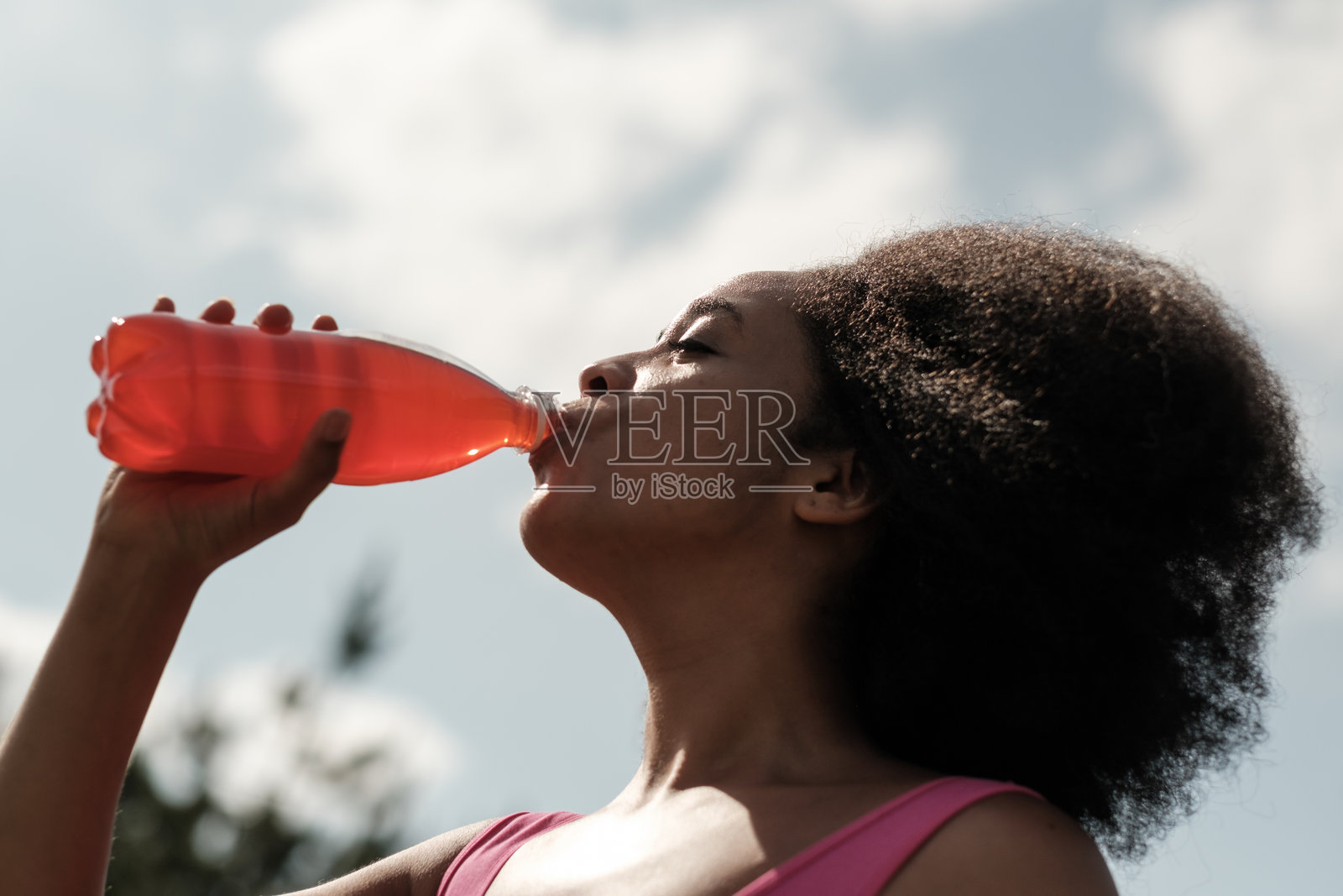 夏天，年轻女子正从塑料瓶中饮用清爽的苏打水照片摄影图片