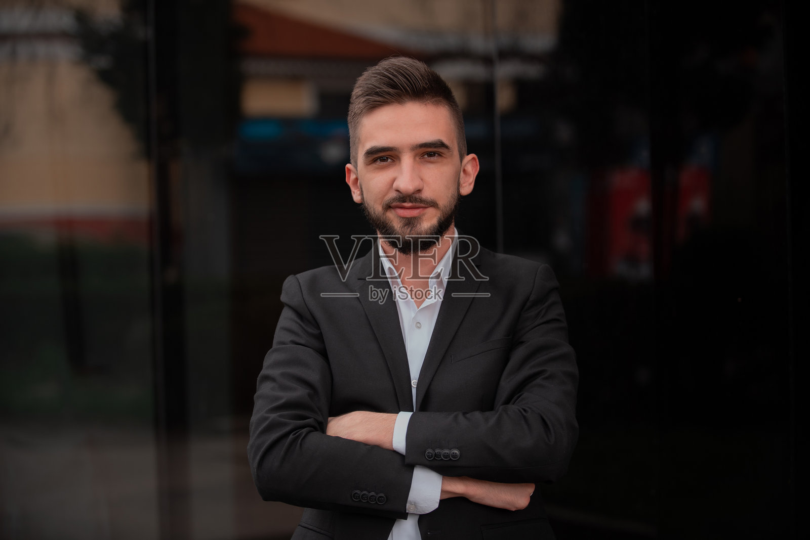 年轻快乐的商务男士肖像，双臂交叉，自信地看着镜头并微笑着。照片摄影图片