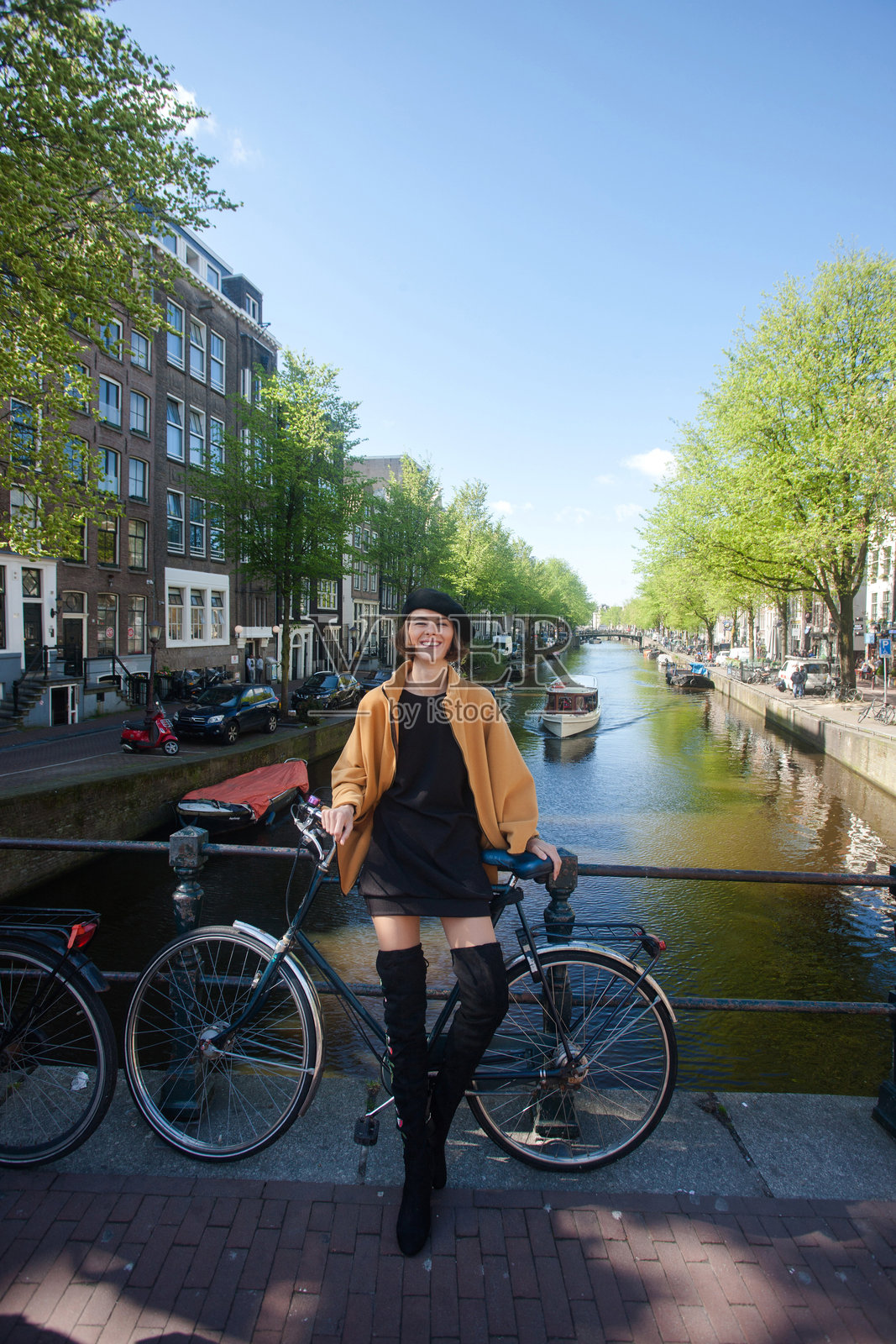 一位时尚美丽的女士，站在阿姆斯特丹运河边，背景是典型的荷兰自行车照片摄影图片