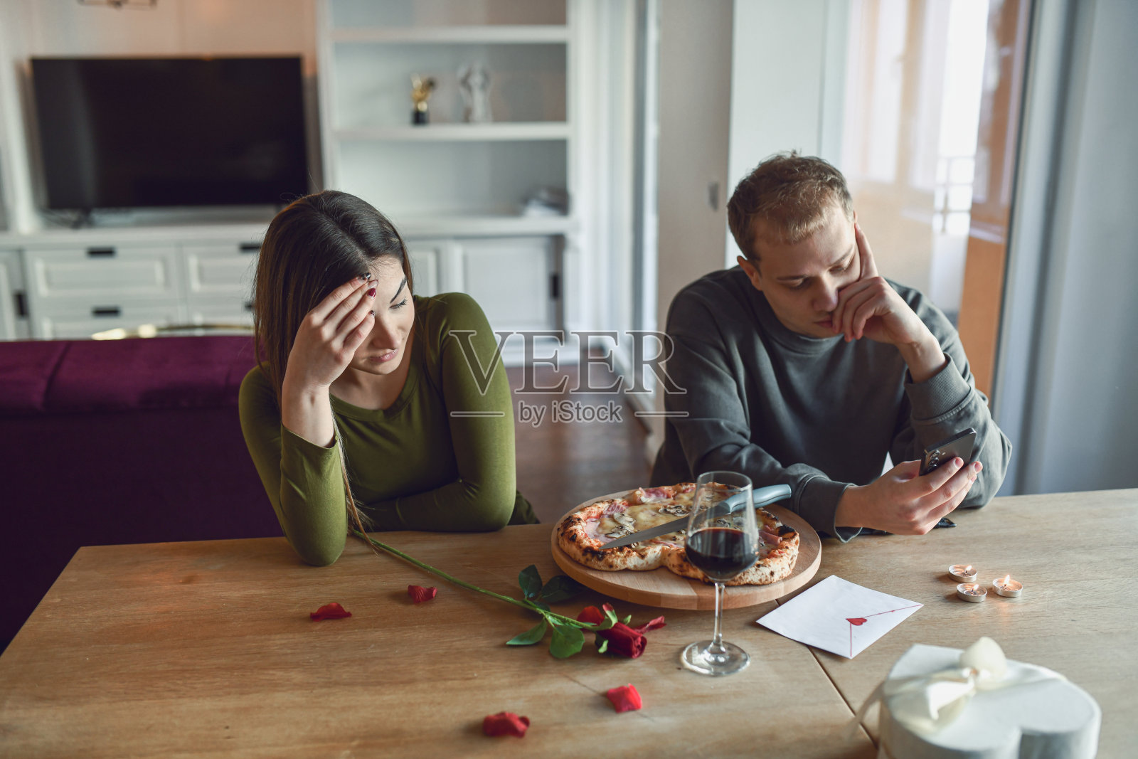 情侣在家紧张地享用情人节晚餐，却被手机分心照片摄影图片