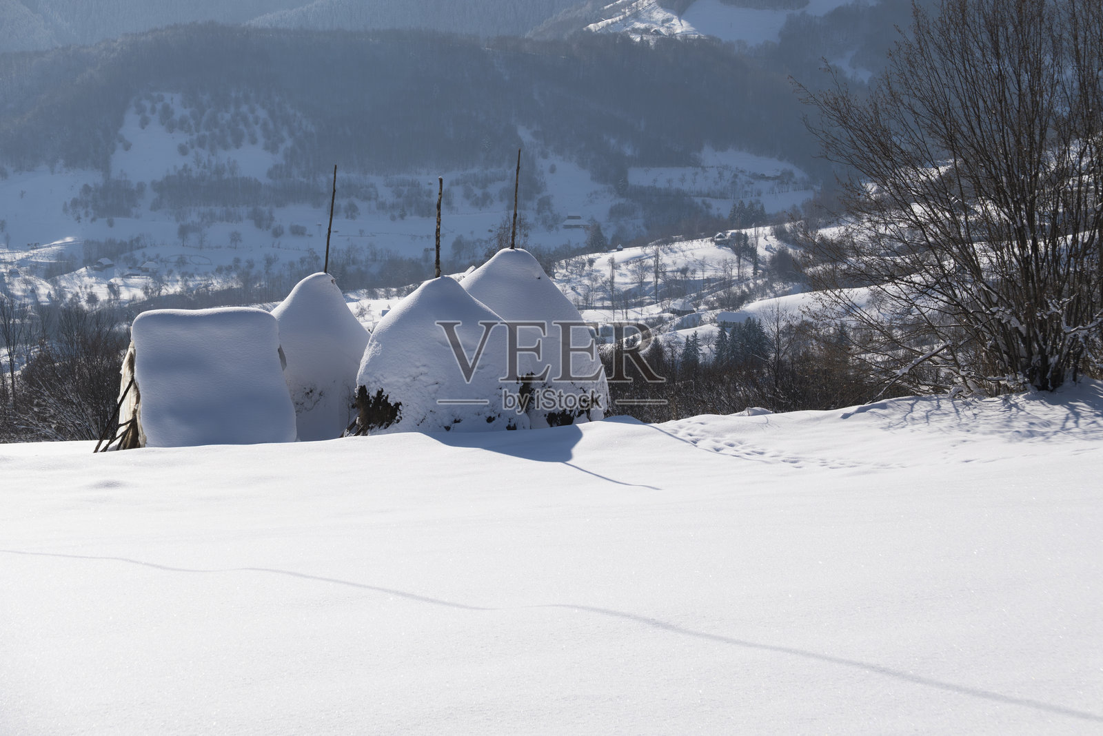 被雪覆盖的标志性乡村干草堆，坐落在山区乡村照片摄影图片