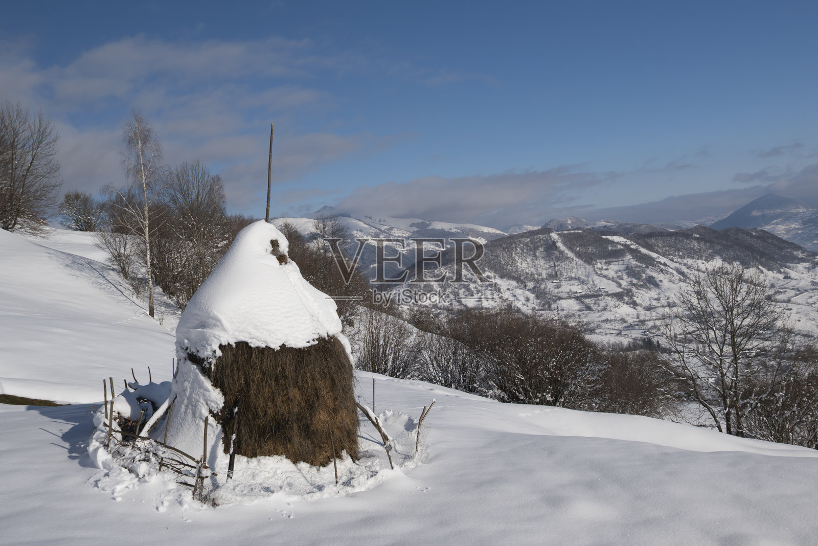 标志性的乡村干草堆，覆盖着山间乡村的雪照片摄影图片