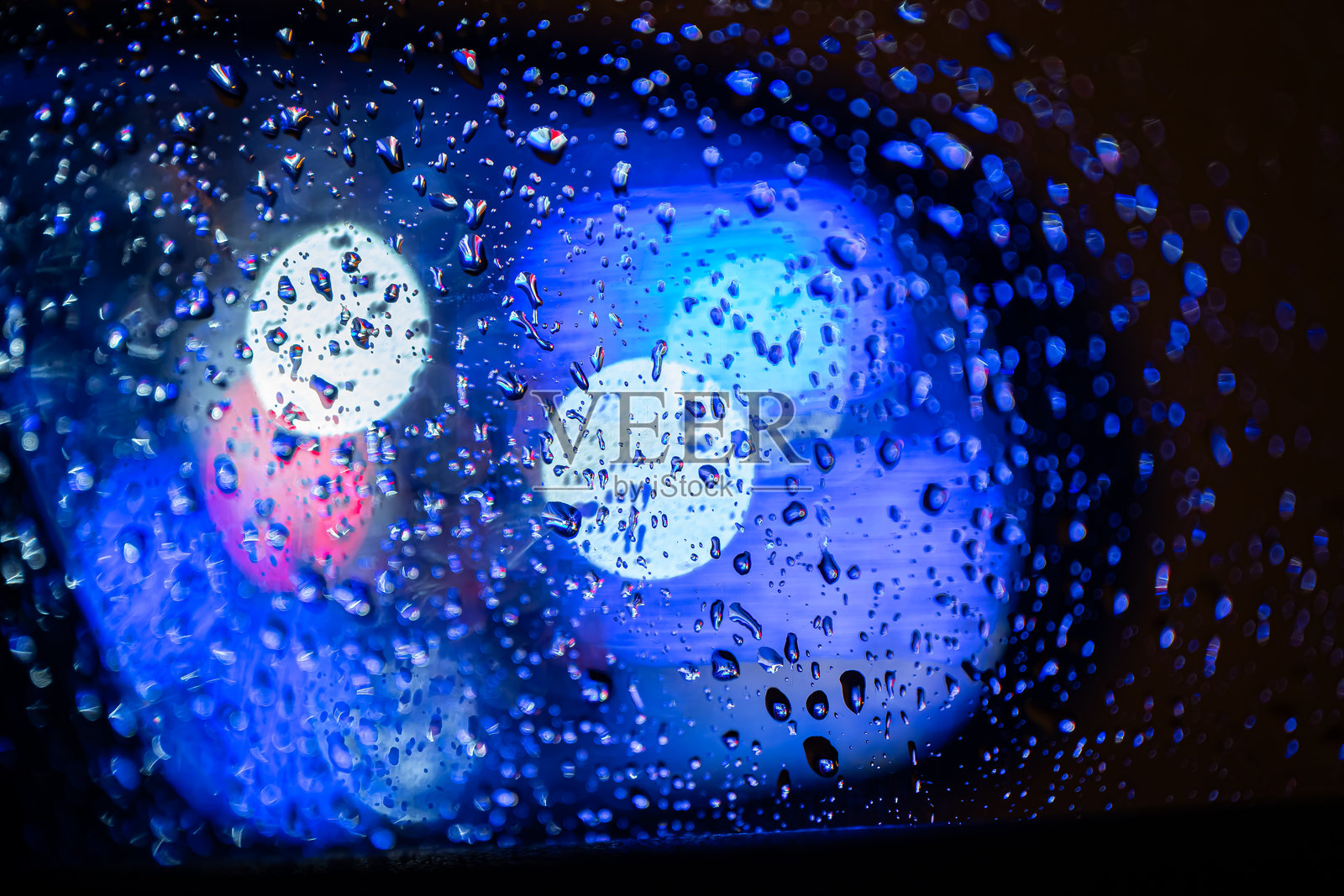 雨滴落在玻璃上，带有汽车灯光散景效果。交通、天气、雨灯的概念。雨天冬日的城市生活。照片摄影图片