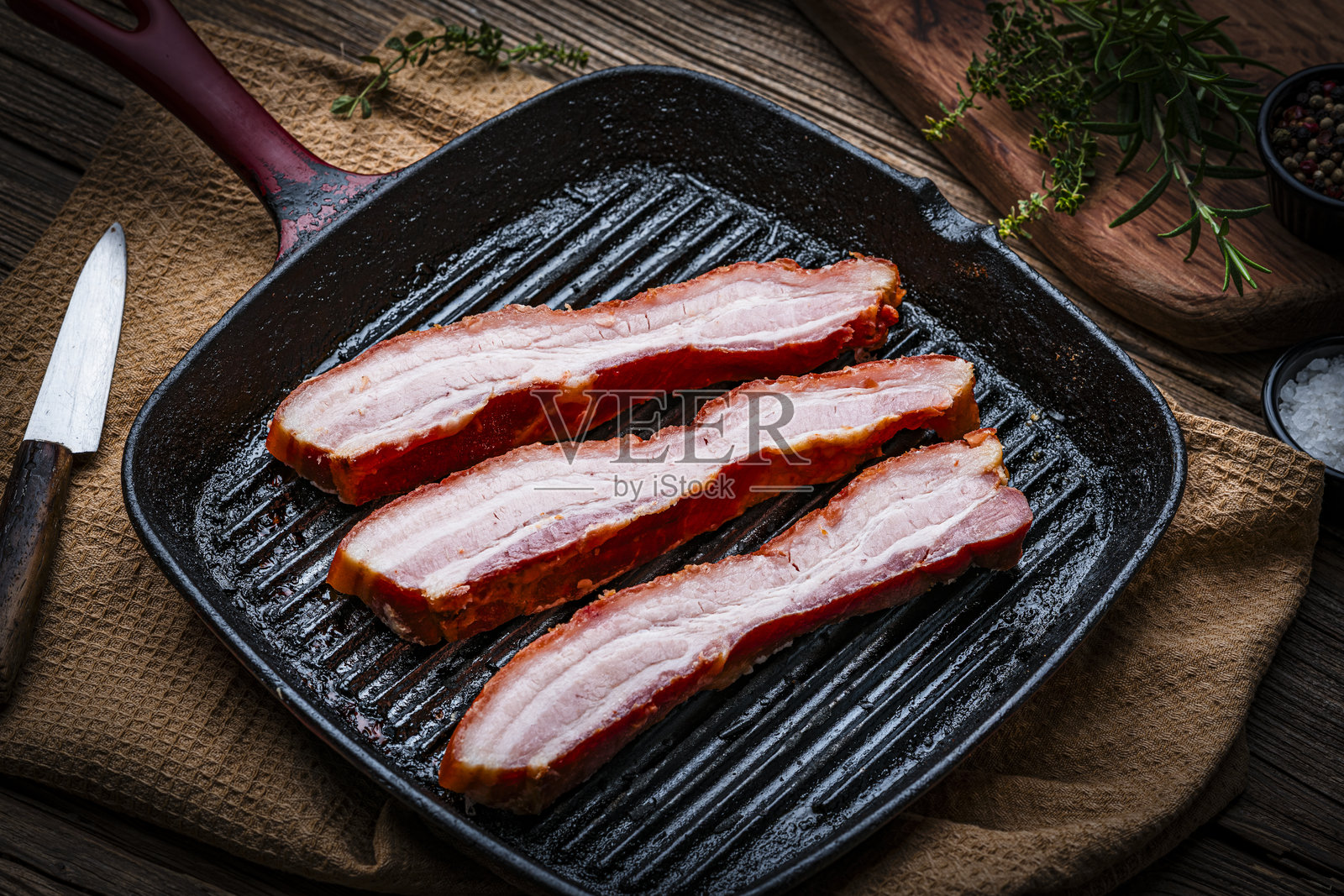 炸猪皮：将带皮的生培根条放在铸铁烤架上准备烹饪。烤制或油炸后，是传统的西班牙小吃或开胃菜。非常酥脆可口。照片摄影图片