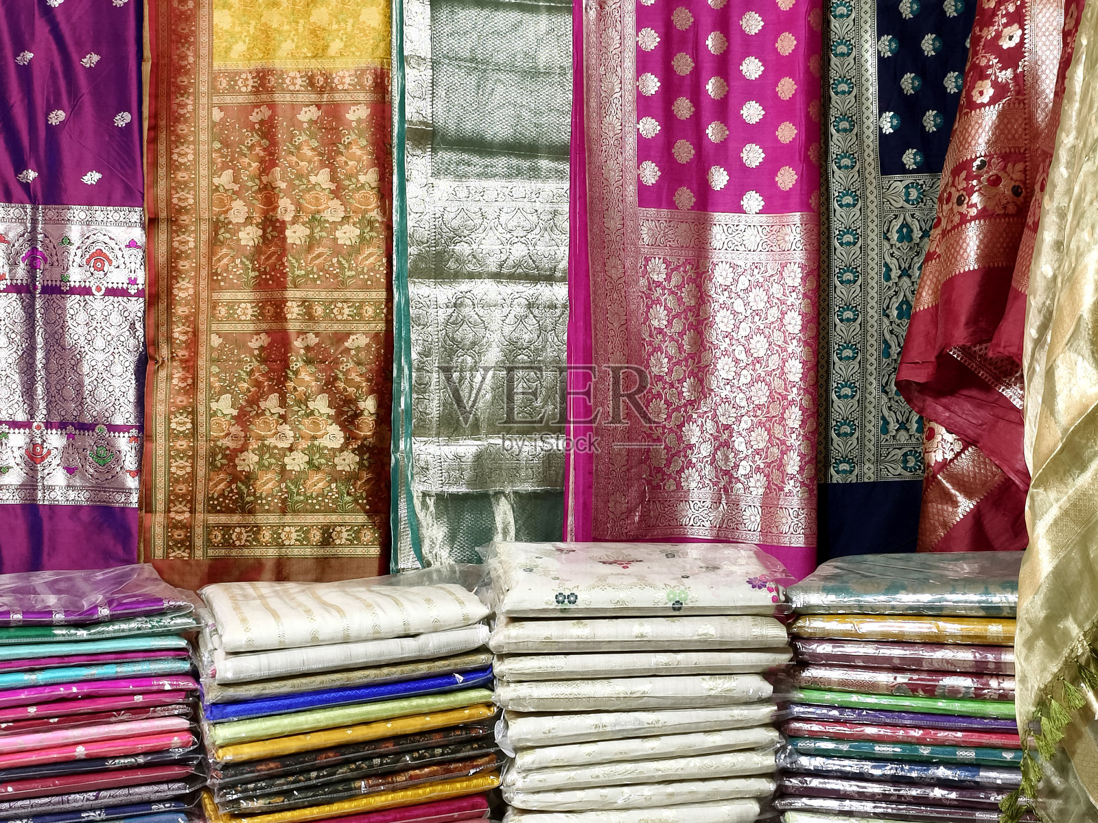 印度零售店、纺织品商店中展示的叠放彩色纱丽的特写照片摄影图片