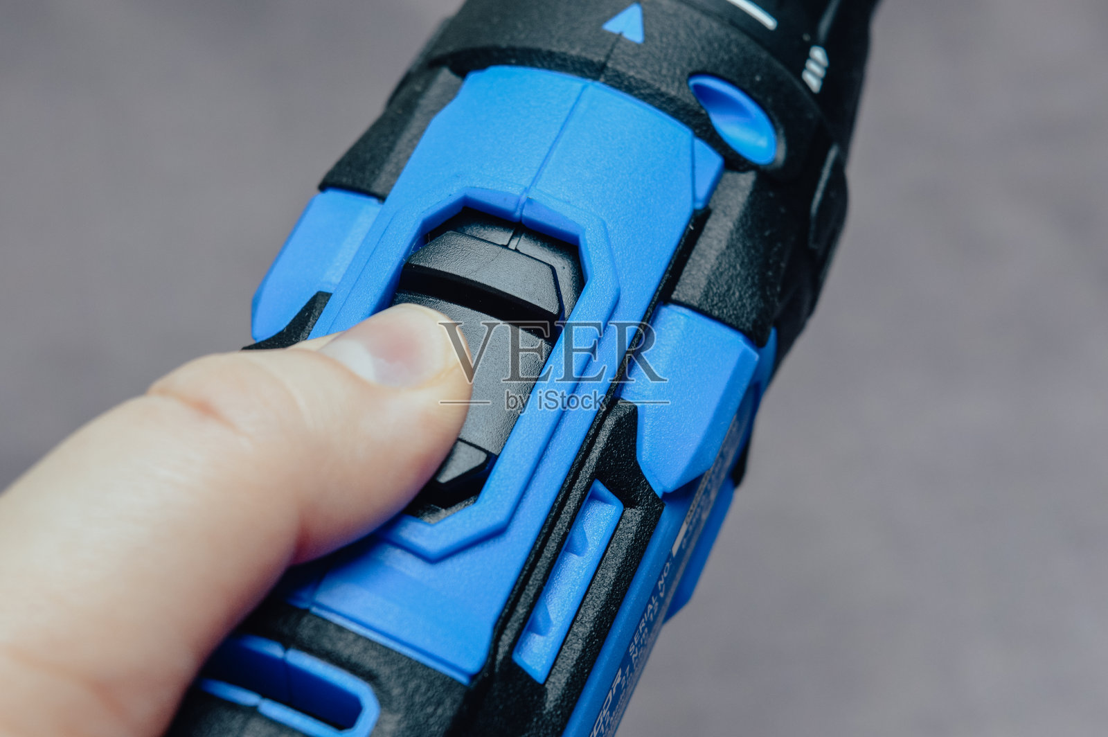无绳电动钻手柄和夹头的特写，带有蓝色和黑色橡胶握把。现代电动工具上的扳机、扭矩设置和 LED 指示灯的详细视图。照片摄影图片