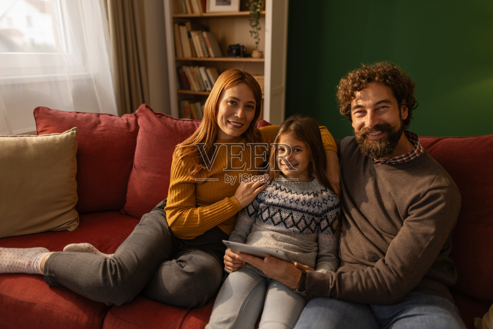 快乐的一家人舒适地坐在沙发上，一起使用平板电脑照片摄影图片
