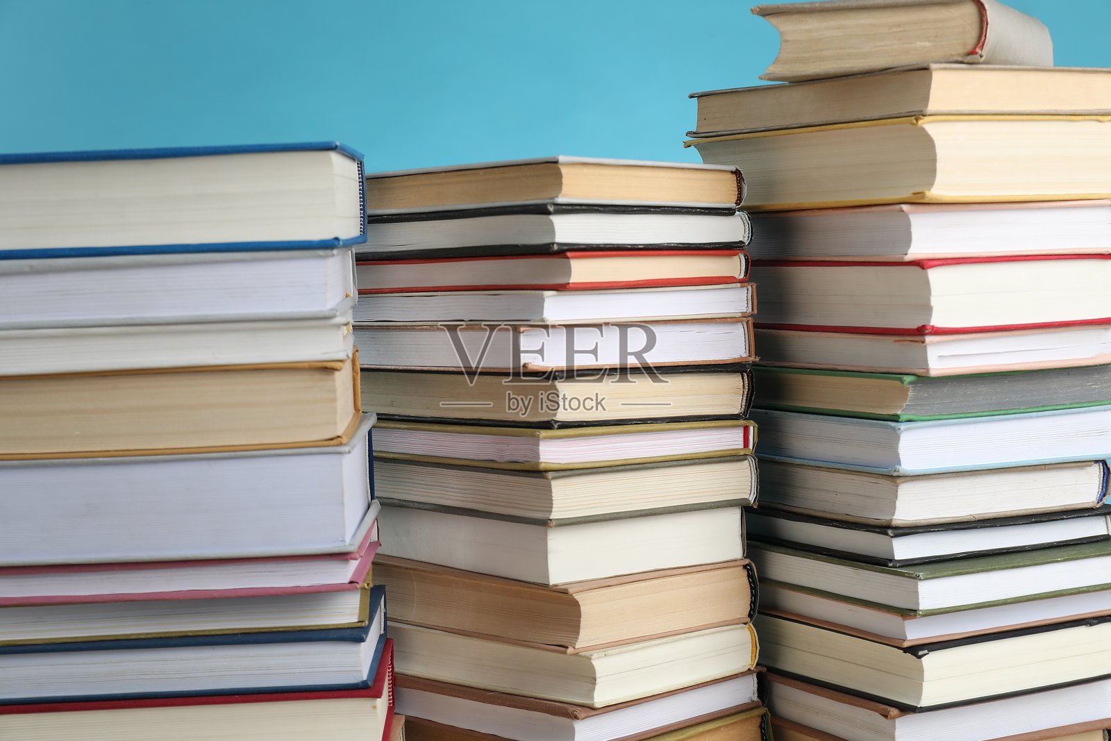 许多堆叠的书本，背景为浅蓝色，特写照片摄影图片