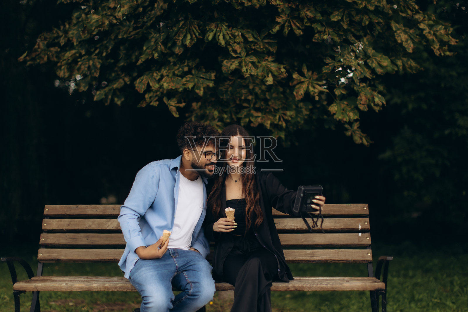 一对多元化的情侣在公园里一边吃冰淇淋一边录制视频博客照片摄影图片