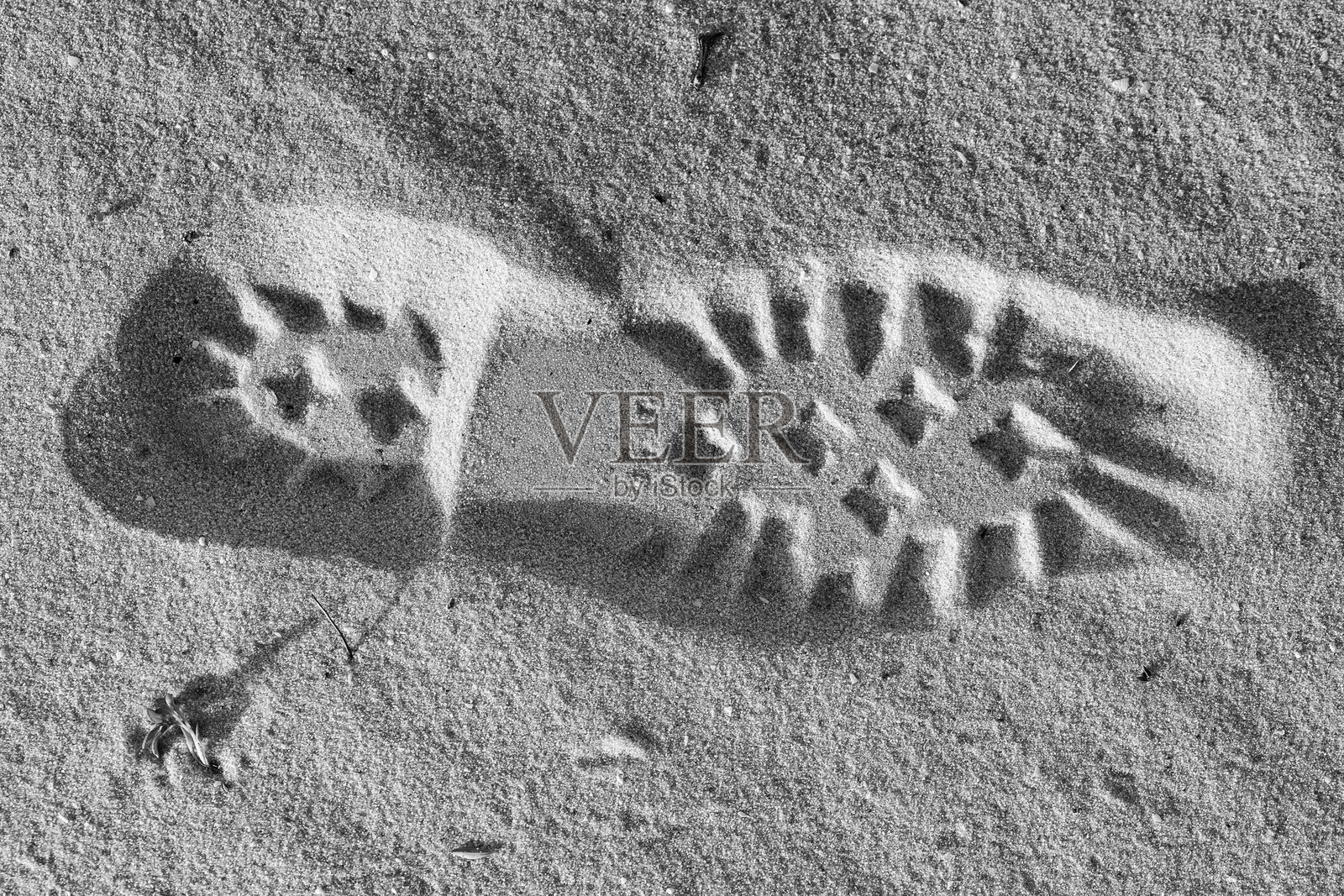 明亮的阳光下，沙滩上留下巨大的鞋印脚印照片摄影图片