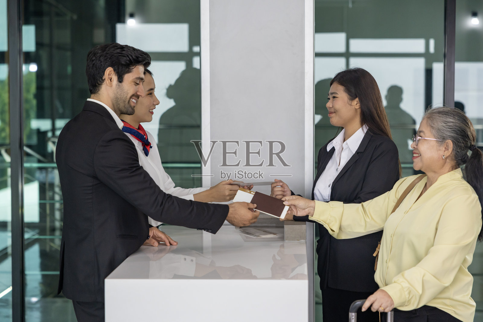 亚洲老年乘客在登机口向航空公司地勤人员出示登机牌，准备在登机前进行最终检查。照片摄影图片