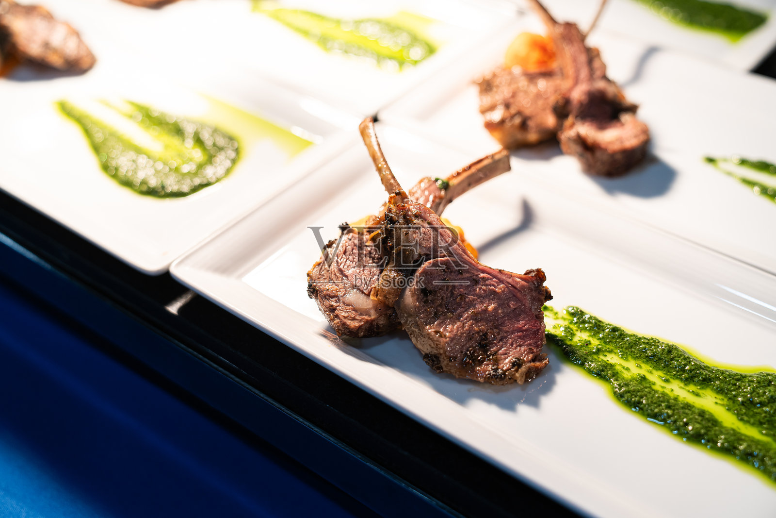 羊排棒棒糖特写，薄切羊肉及绿色酱汁，作为大型活动自助餐的一部分，由专业餐饮团队提供照片摄影图片