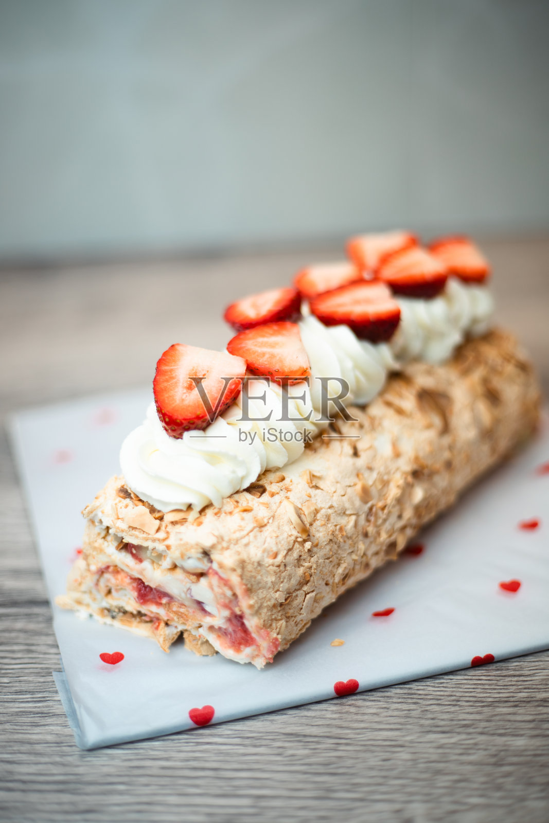 餐桌上装饰着爱心，上面放着覆盆子蛋白卷、新鲜草莓和奶油照片摄影图片