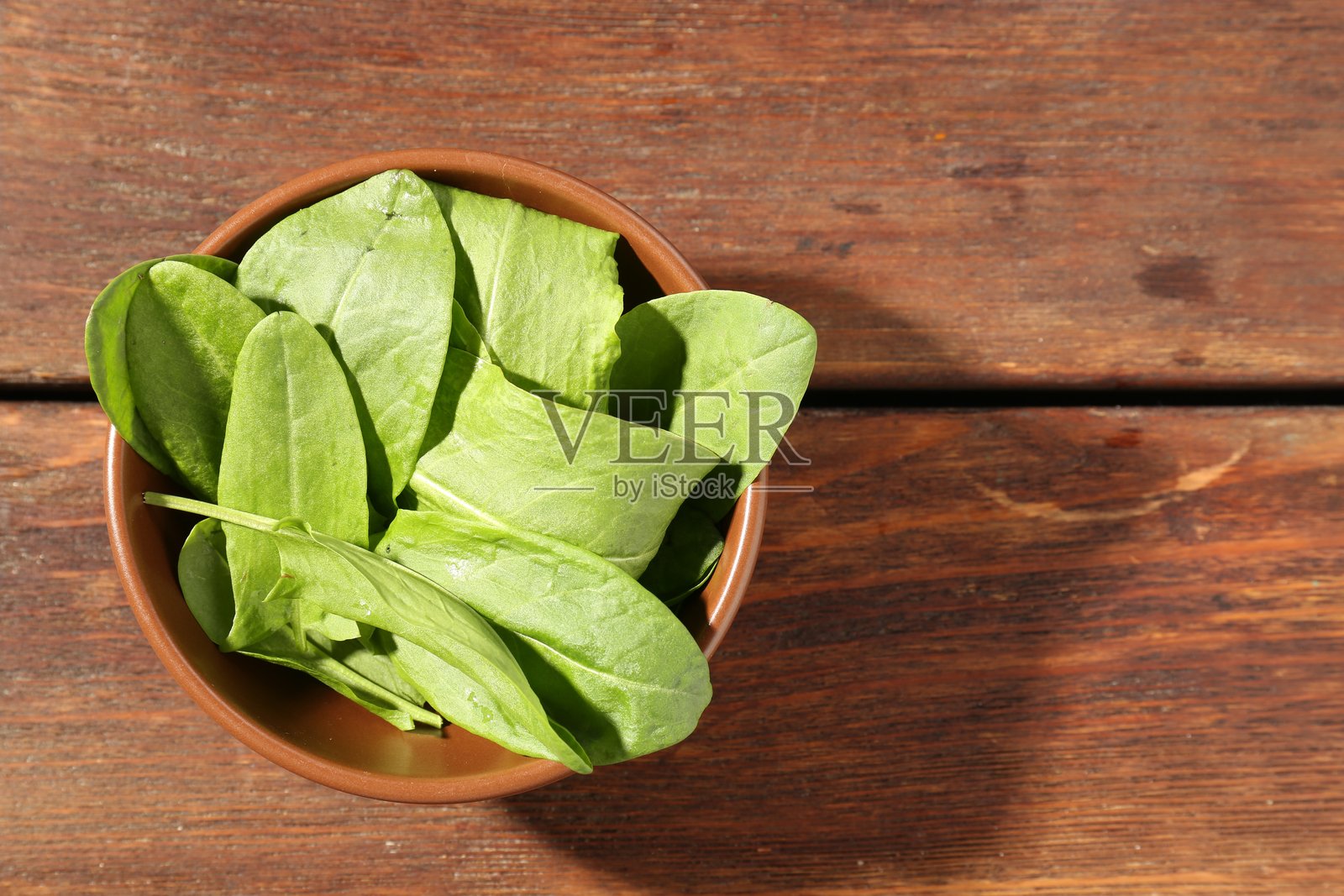 碗里新鲜的绿酸模叶放在木桌上，俯视。留有文字空间照片摄影图片