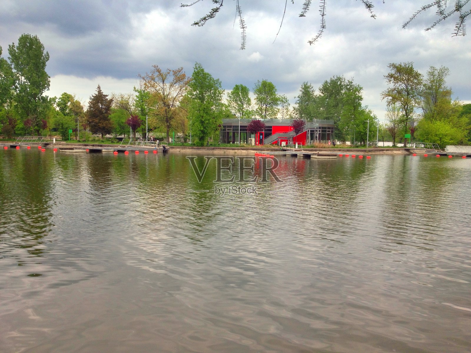 宁静的湖滨公园，有红色现代建筑、漂浮码头和茂密的树木照片摄影图片