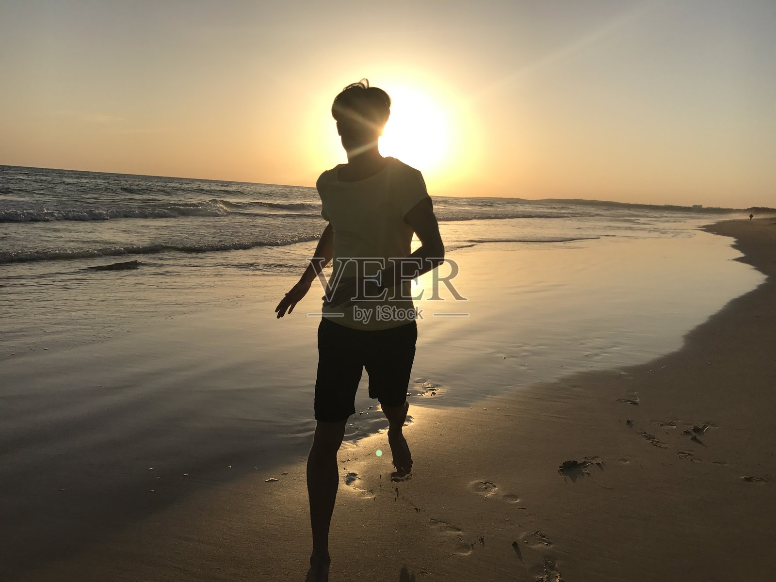 海边跑道上，年轻的运动型男全身剪影正在奔跑照片摄影图片