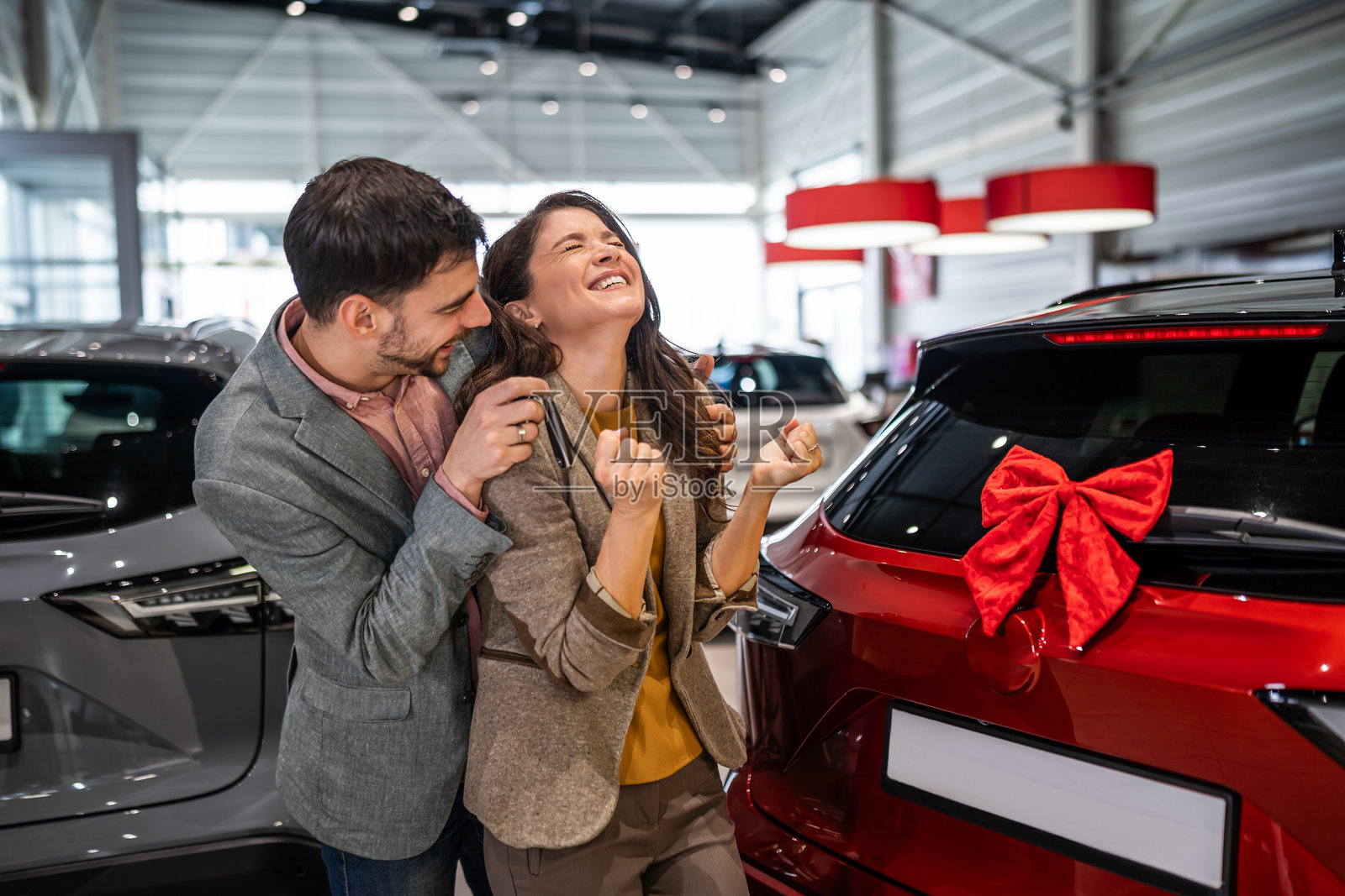 情侣在展厅惊喜庆祝获得新车钥匙照片摄影图片