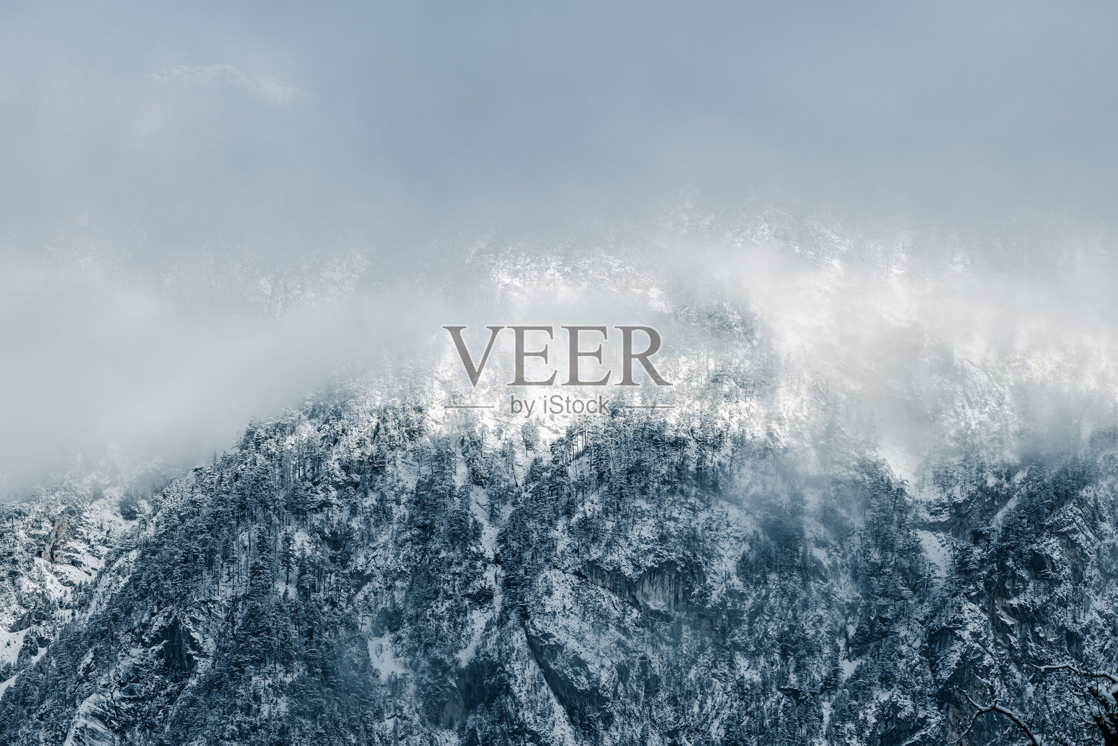 被薄雾笼罩的白雪覆盖的山峰照片摄影图片