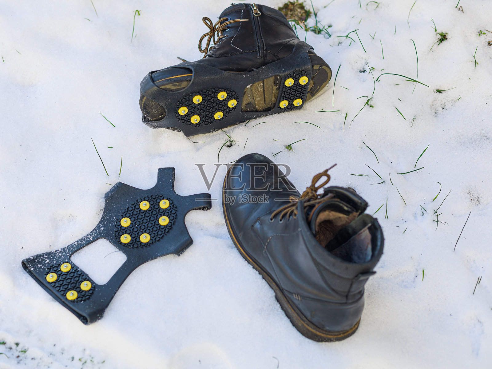冬季靴子和防滑钉放在户外的雪地上。冬季行走安全、鞋靴准备、旅行装备、零售内容的理念。照片摄影图片