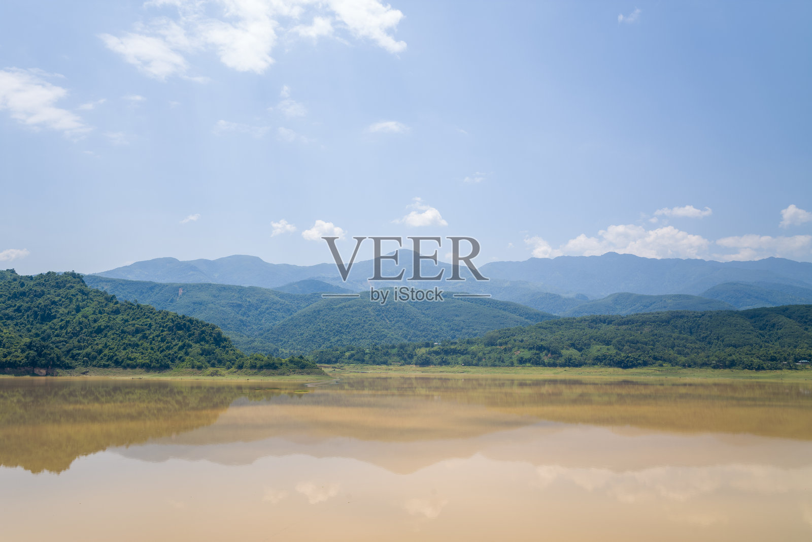 越南平静的泥泞河流倒映着绿色山丘照片摄影图片