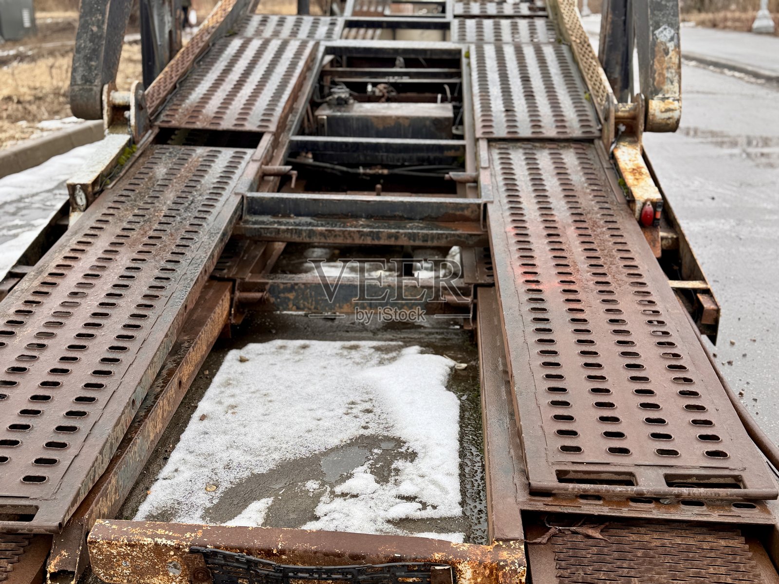 破旧的拖车在雨中废弃生锈，废弃的车辆被遗弃在乡村湿漉漉的街道上，被遗弃的拖车在荒凉的乡村环境中因生锈的部件而日渐破败照片摄影图片
