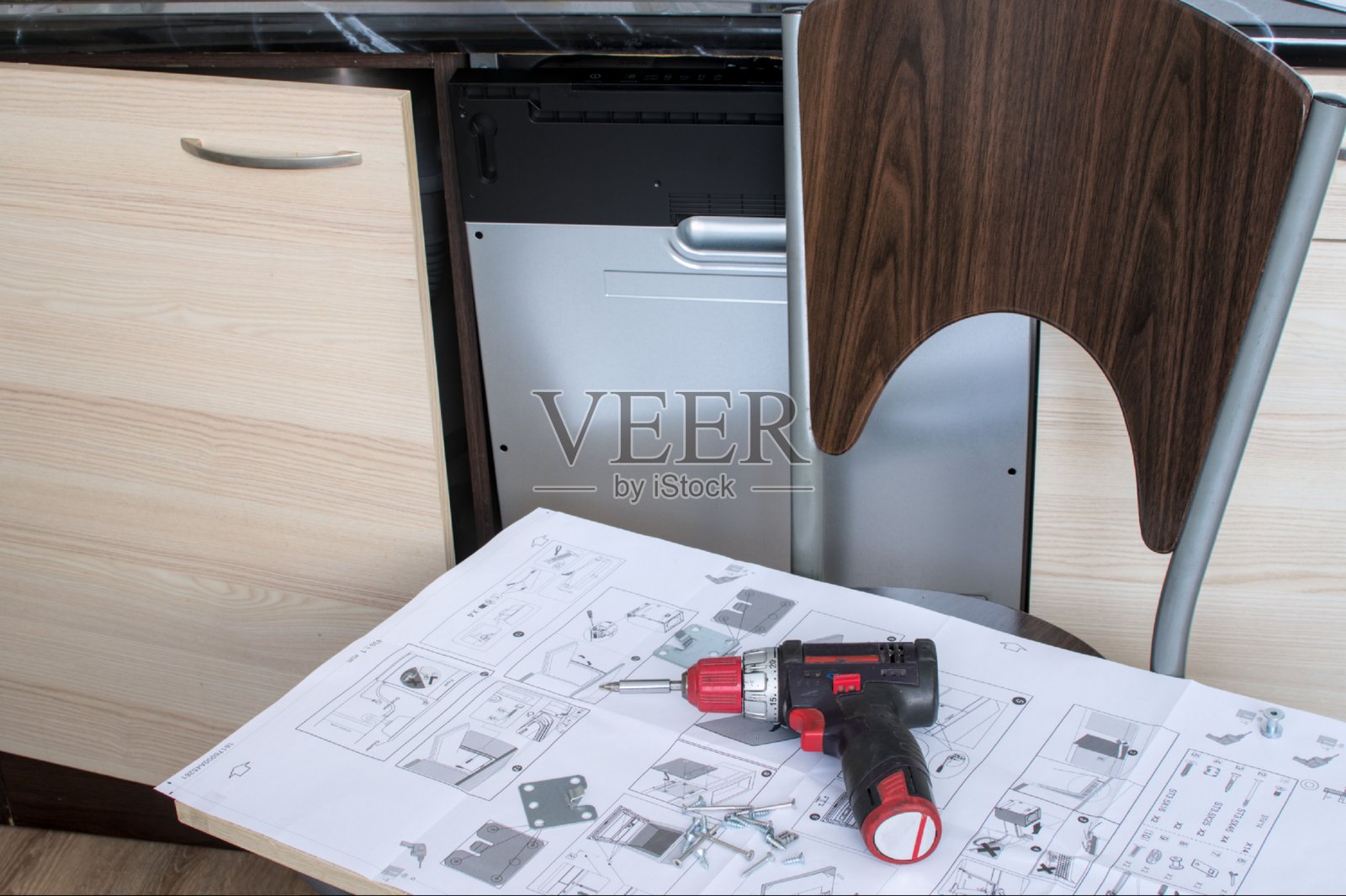 厨房地板上洗碗机安装过程的特写，附有说明书和工具。照片摄影图片