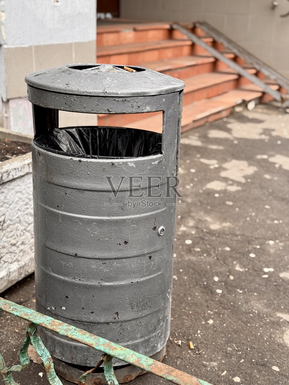 金属户外垃圾桶，带塑料内衬和污渍的户外金属垃圾桶，专为户外使用设计的带污渍和塑料内衬的圆柱形金属垃圾容器照片摄影图片