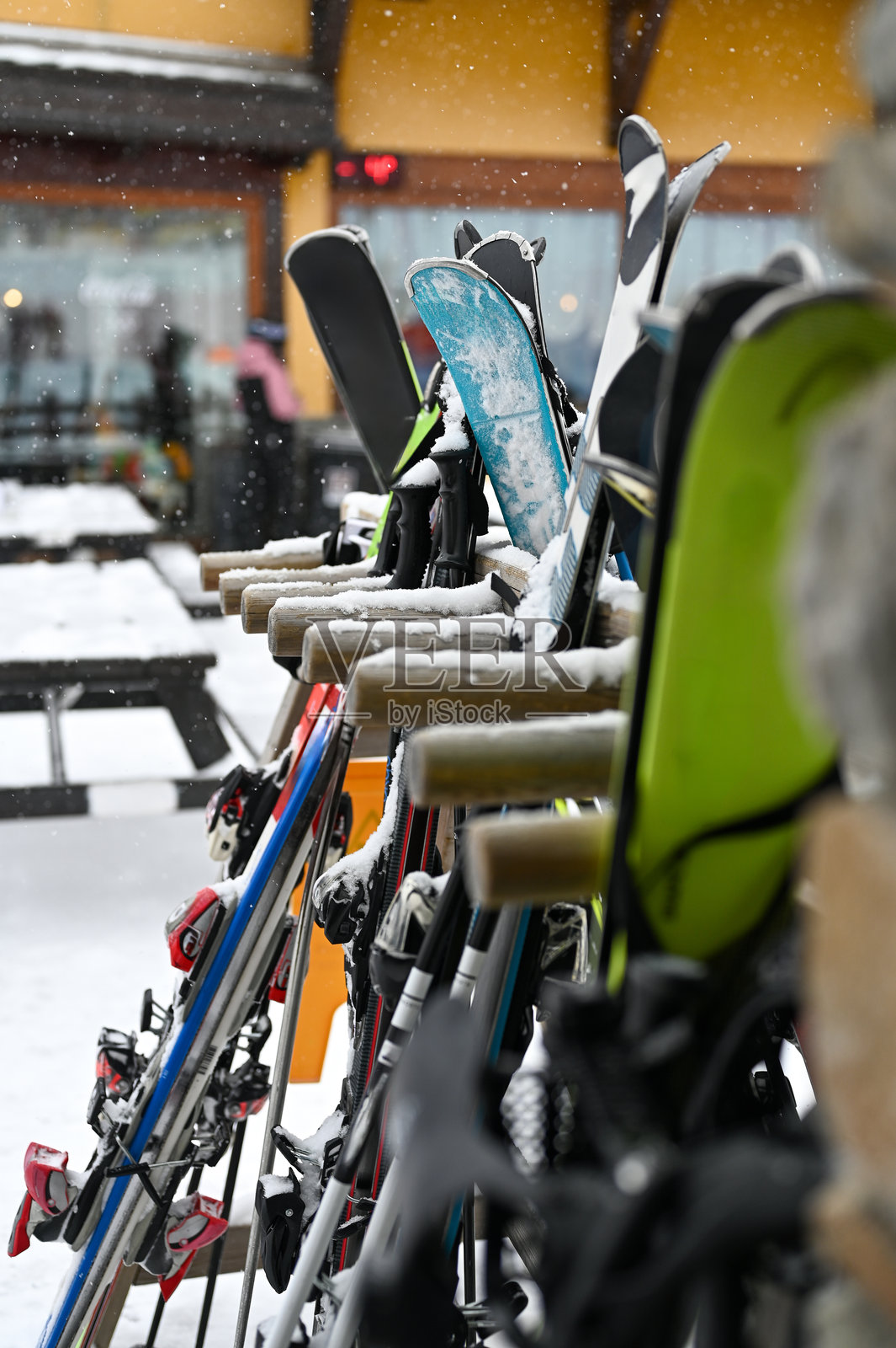 滑雪板放在架子上，架子覆盖着度假村外的积雪照片摄影图片