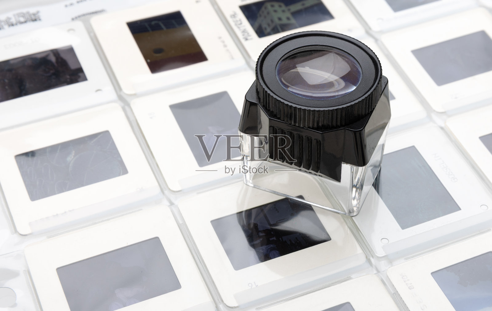 幻灯片胶片存放在塑料观片夹中，并在灯箱上配有放大镜照片摄影图片